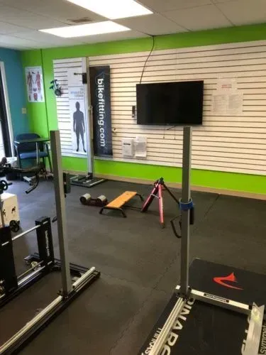 A gym with a treadmill and a tv on the wall