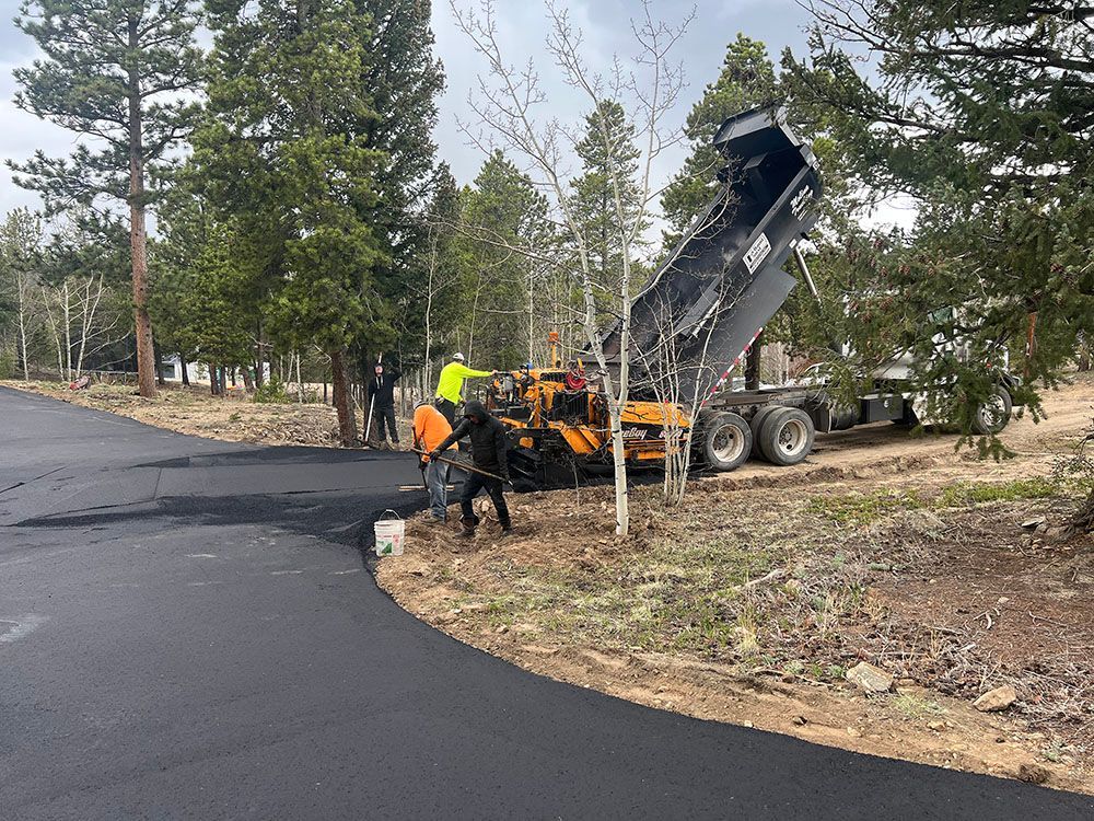 a dump truck is being loaded with asphalt on a road.