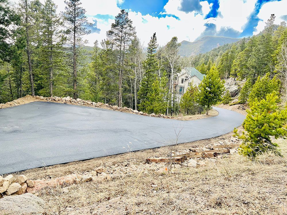 a road going through a forest with a house in the background.