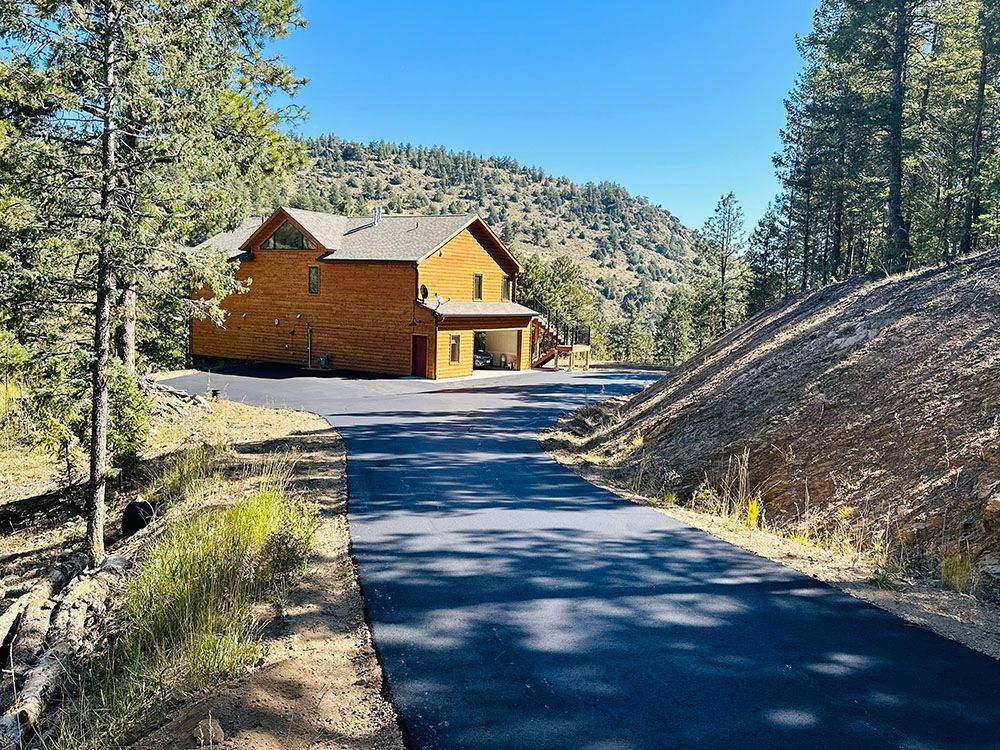 a large wooden house is sitting on top of a hill next to a road.