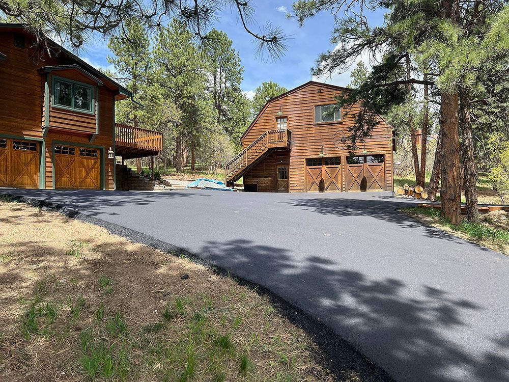 a large wooden house with a large driveway in front of it.