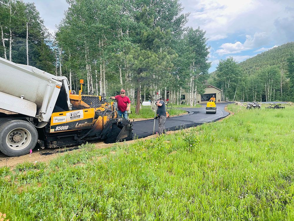 a truck is being loaded with asphalt in a field.