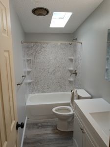 A bathroom with a bathtub , toilet , sink and skylight.