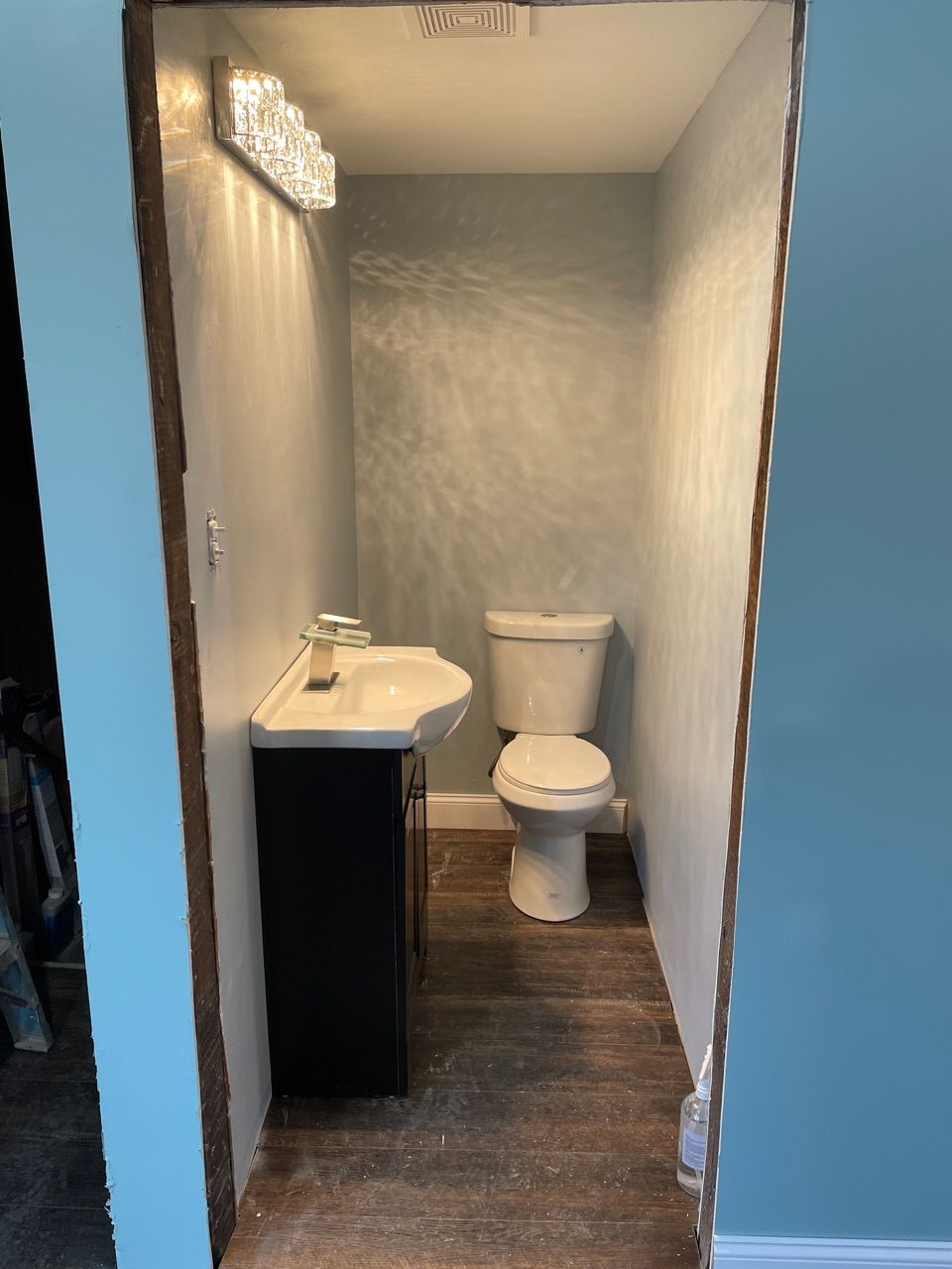 A bathroom with a toilet , sink and light.