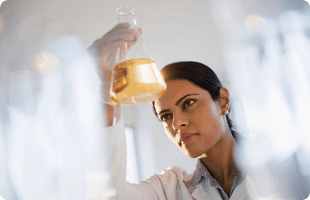 A lady holding a erlenmeyer flask with chemical
