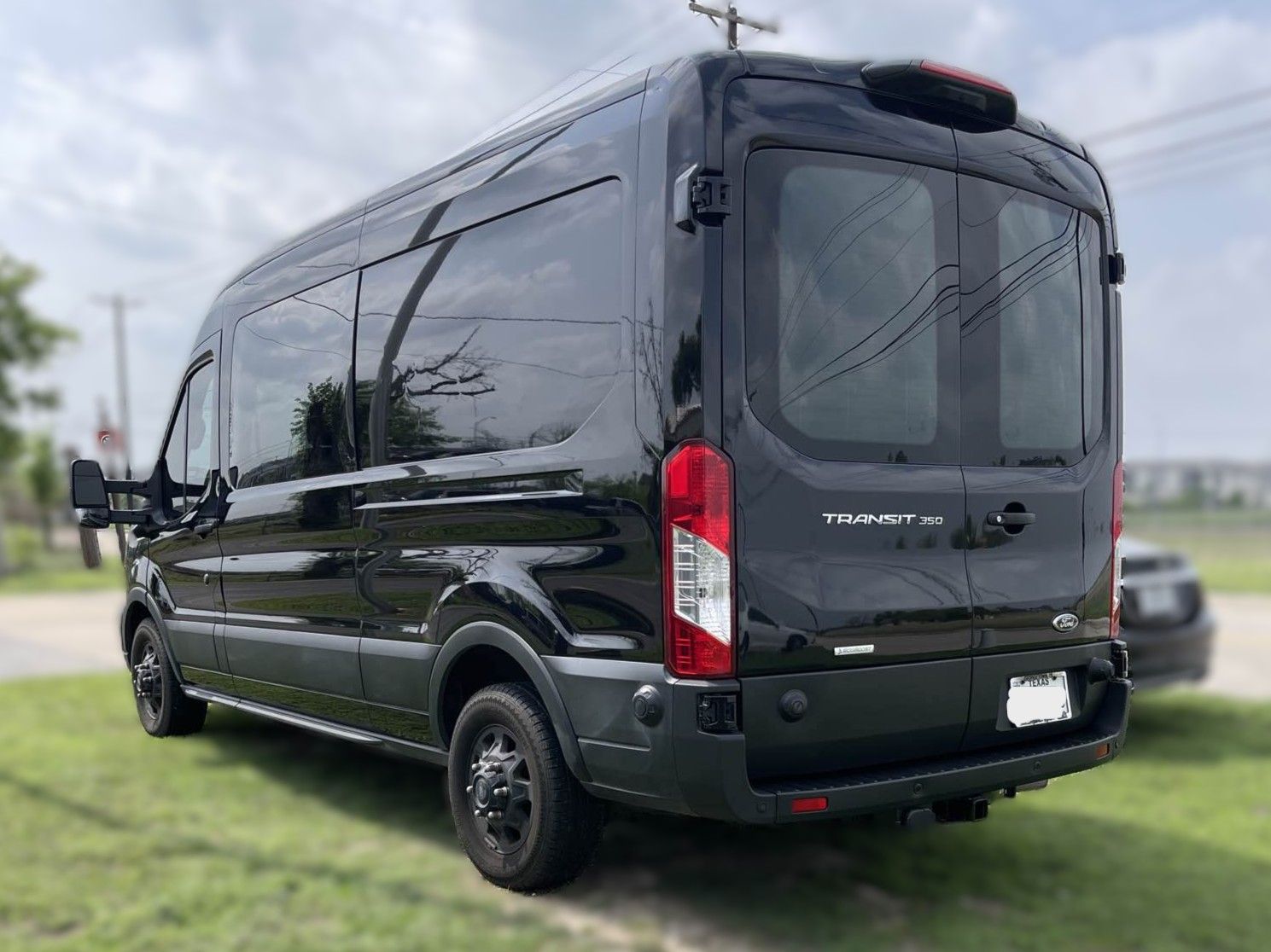 Black Ford Transit van parked on grass.