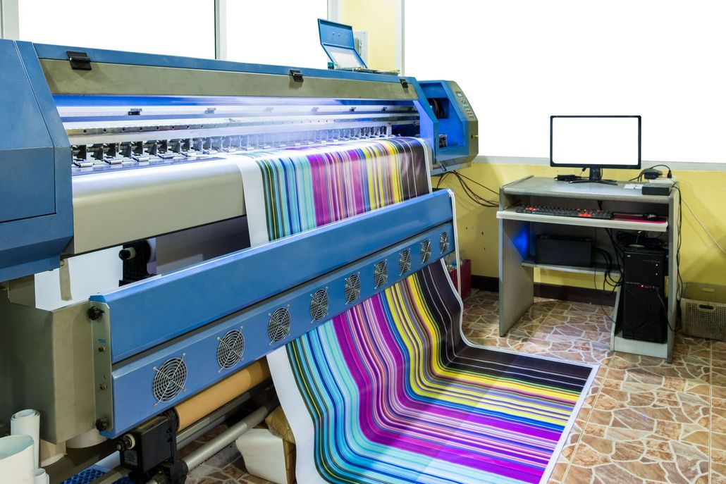 Large format printer printing colorful banner in a brightly lit room.