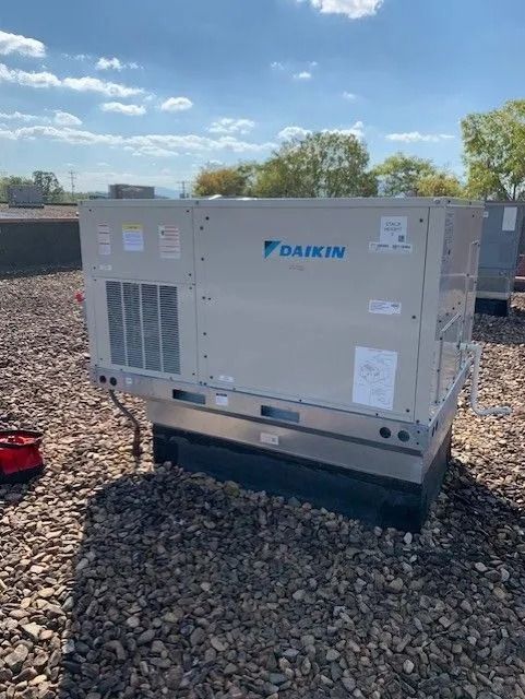 Daikin rooftop HVAC unit on a gravel surface with a blue sky background.