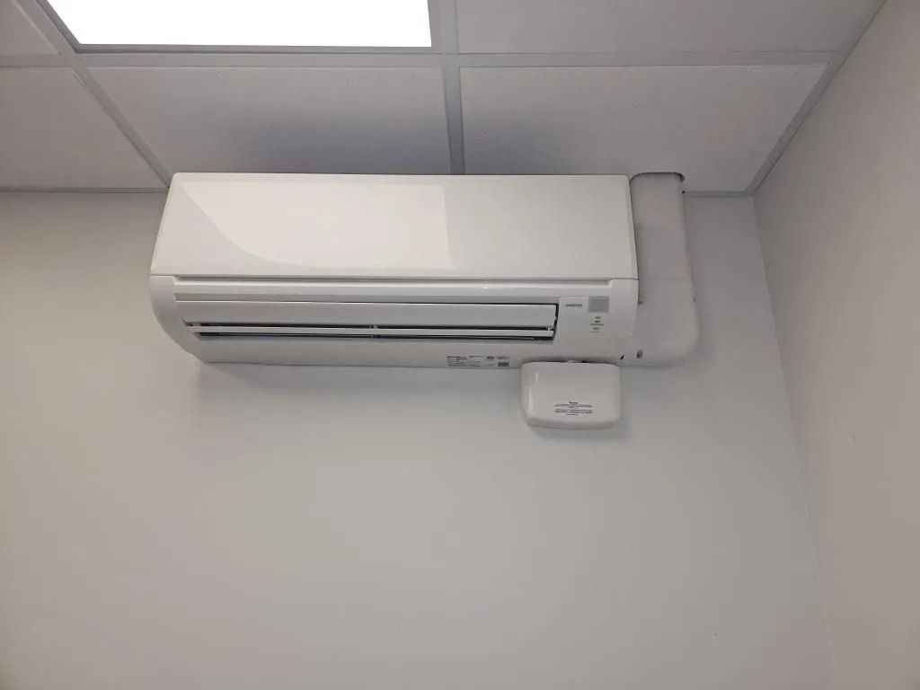 White air conditioning unit mounted on a white wall in a room.
