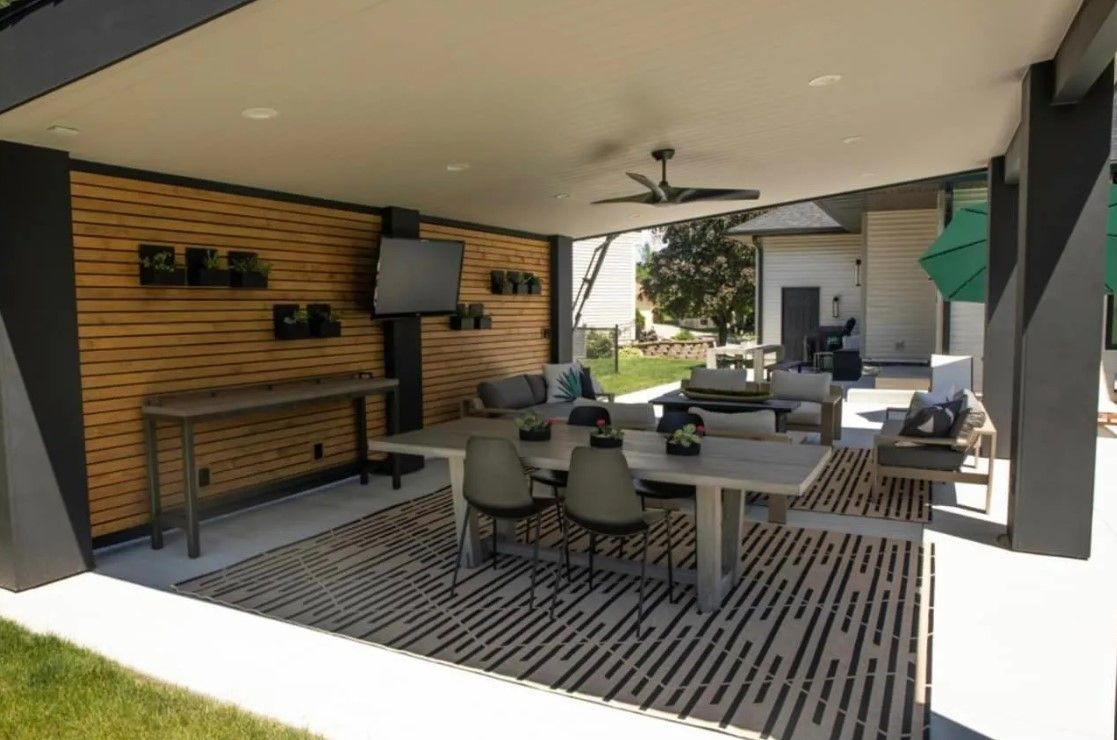 Pool with blue water, surrounded by gray deck, lawn, lounge chairs, and an umbrella on a cloudy day.