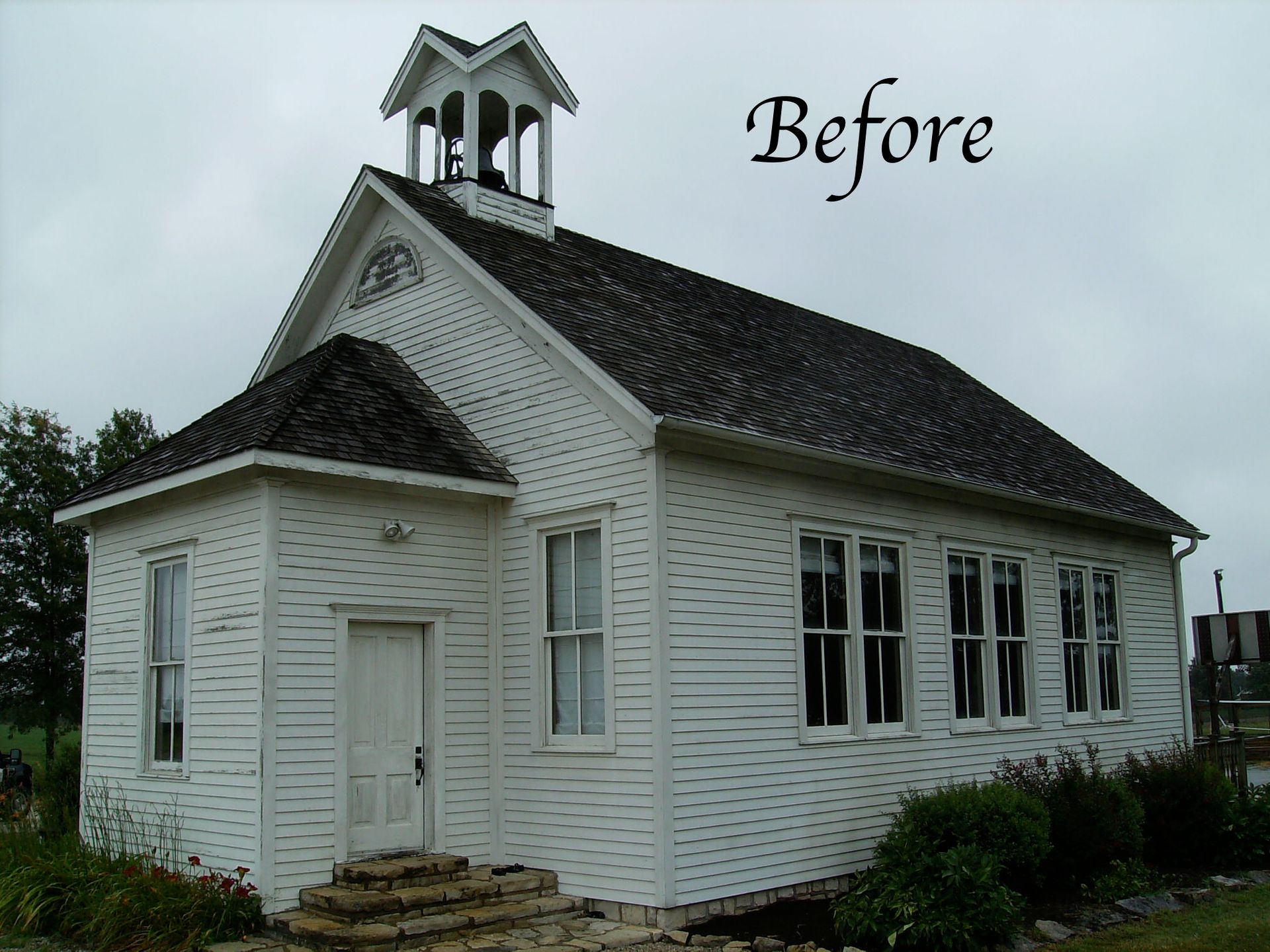 Before photo of a small white church with a steeple and dark roof