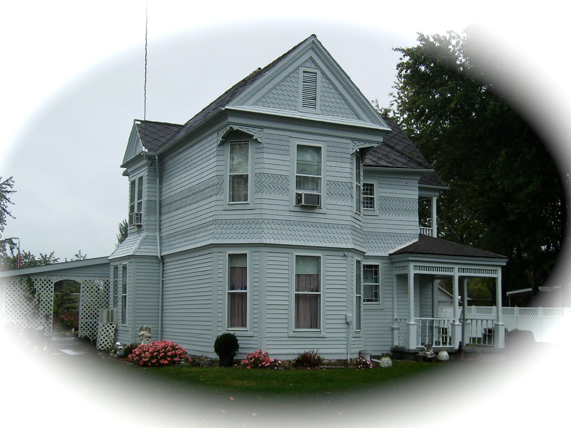 White two-story Victorian house with porch and dormer windows, viewed from the front yard