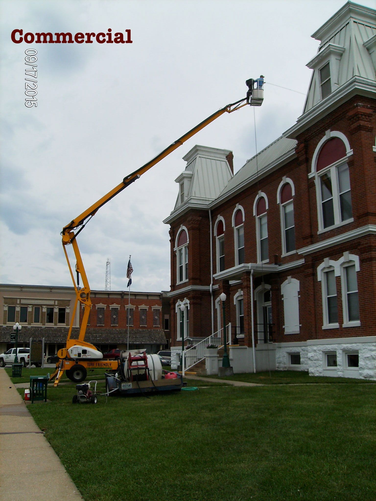 Cherry picker lifting workers beside a red-brick commercial building under renovation