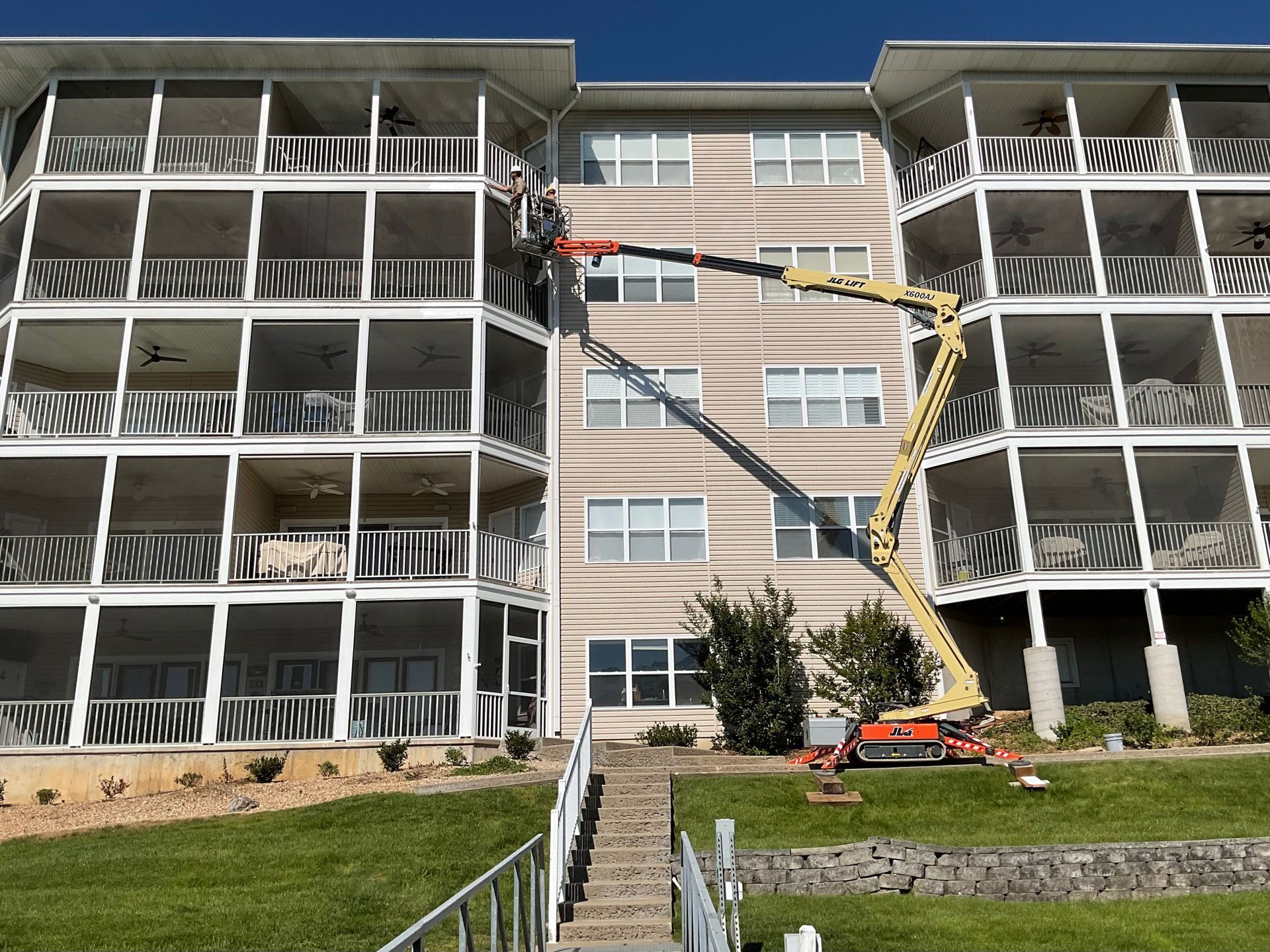 Construction workers on a building exterior, with a lift reaching the upper balconies.