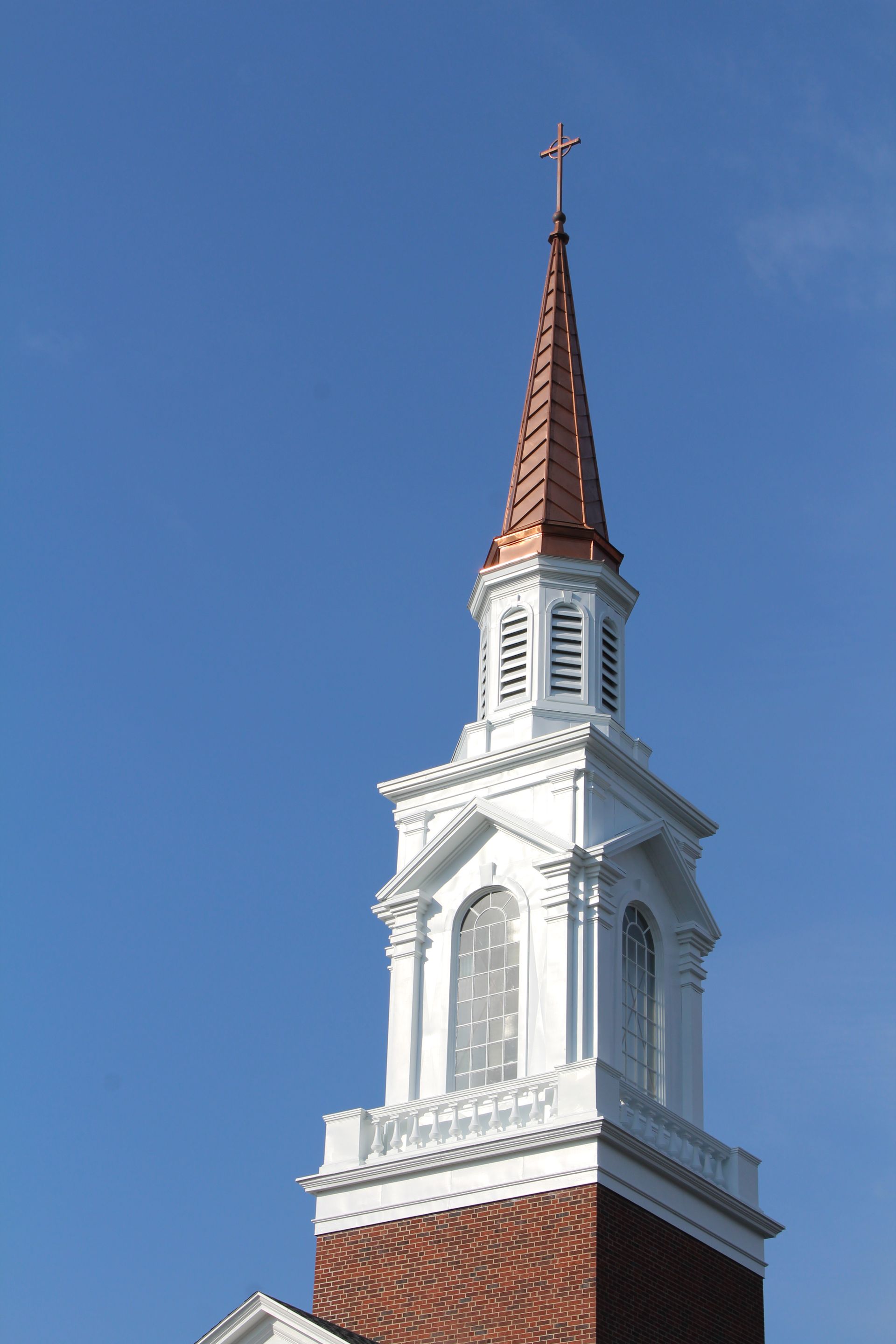 White church steeple with a copper spire against a clear blue sky