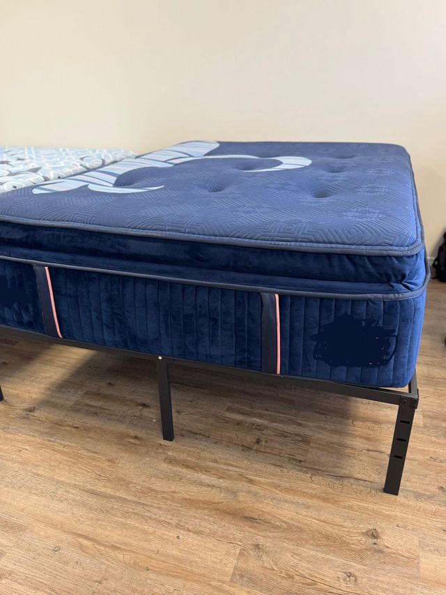 Blue upholstered bed frame with mattress in a room with wood flooring
