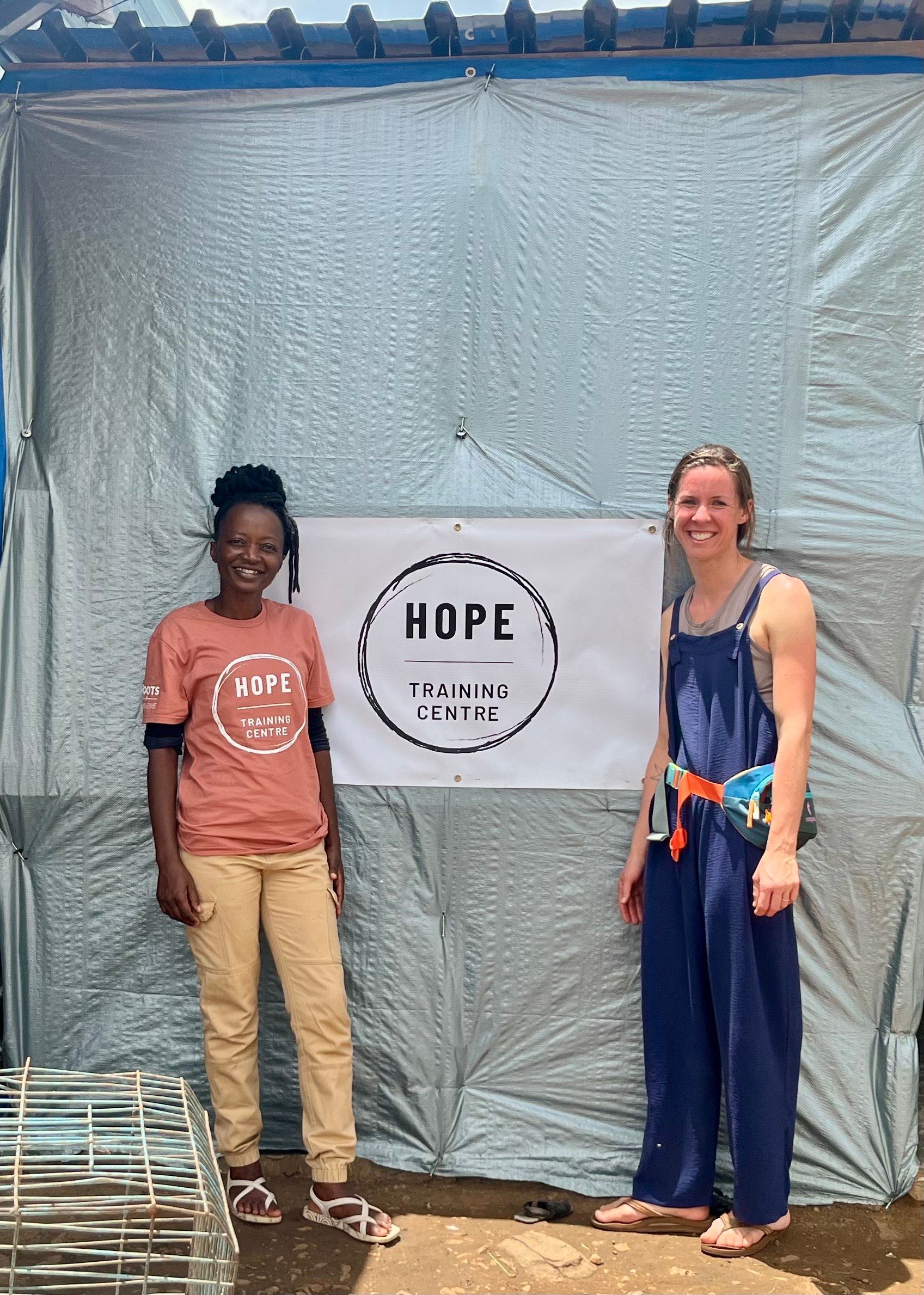 Two people are standing in front of a tent with a sign that says hope.