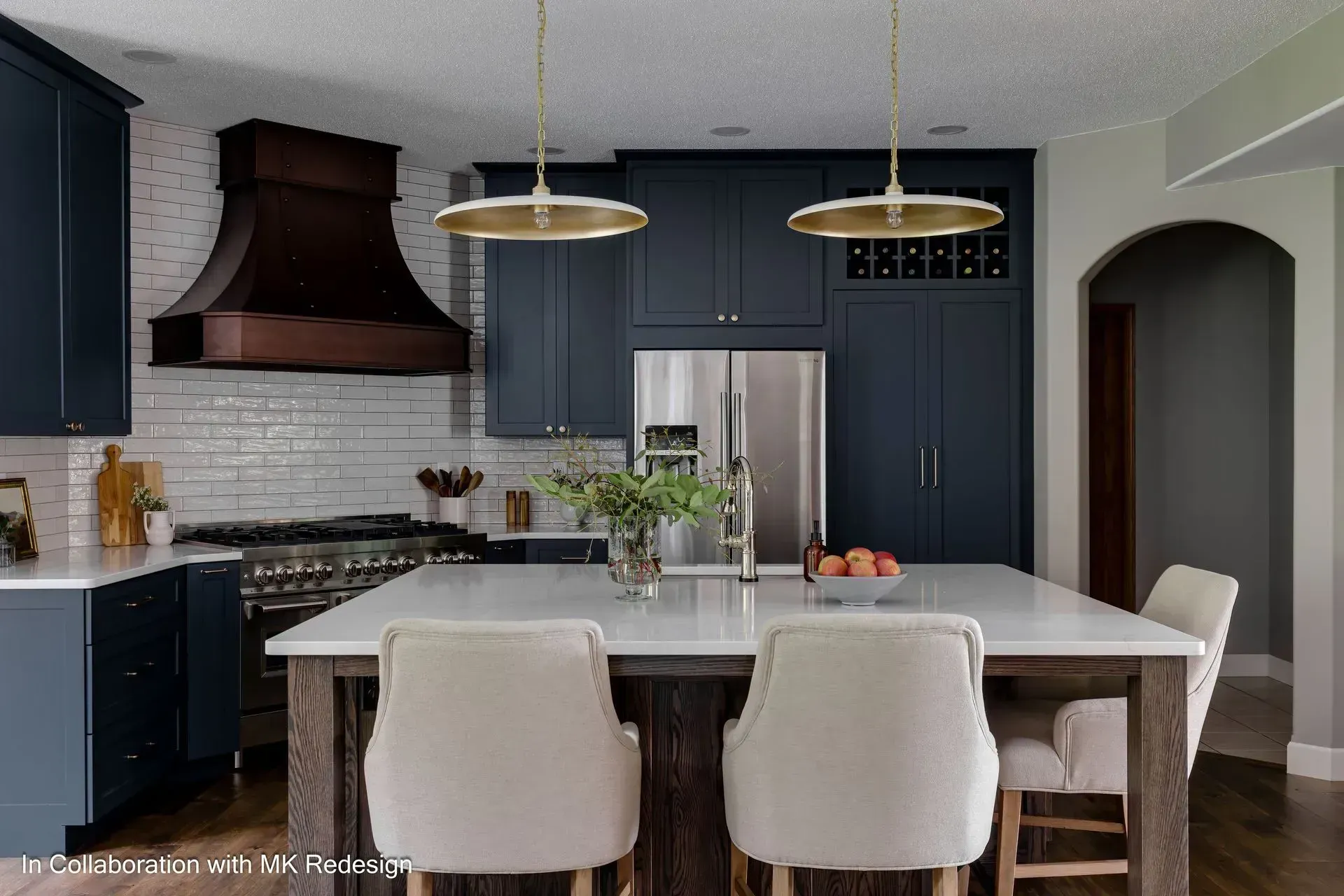 A kitchen with blue cabinets , white counter tops , stainless steel appliances and a large island.