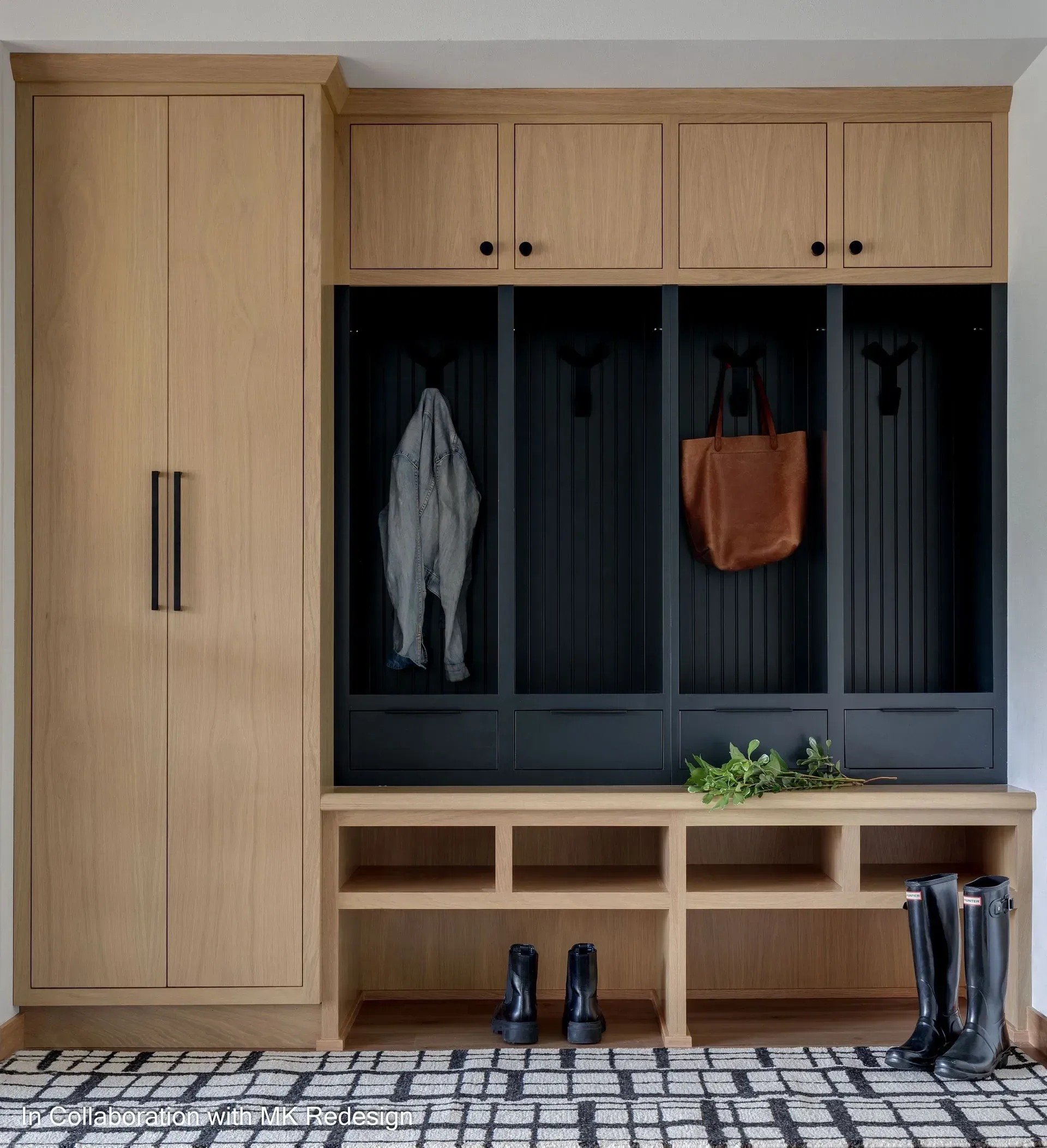 A mud room with wooden cabinets , a bench , boots , and a bag hanging on the wall.