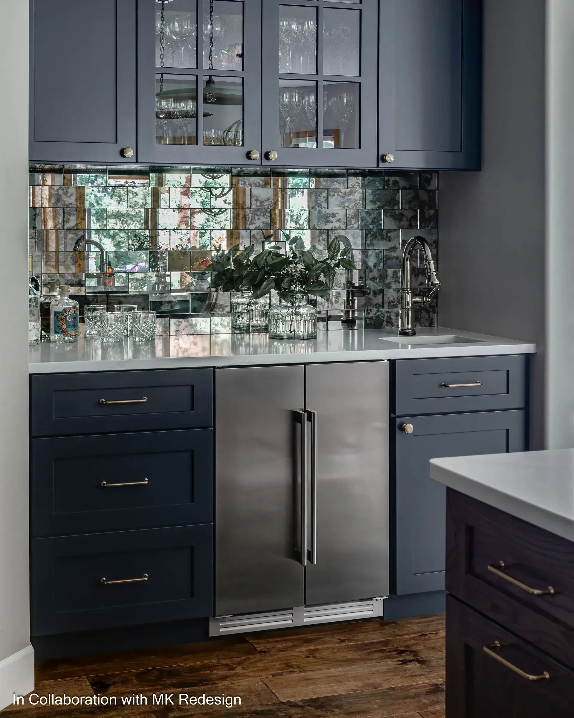 A kitchen with blue cabinets and a stainless steel refrigerator.