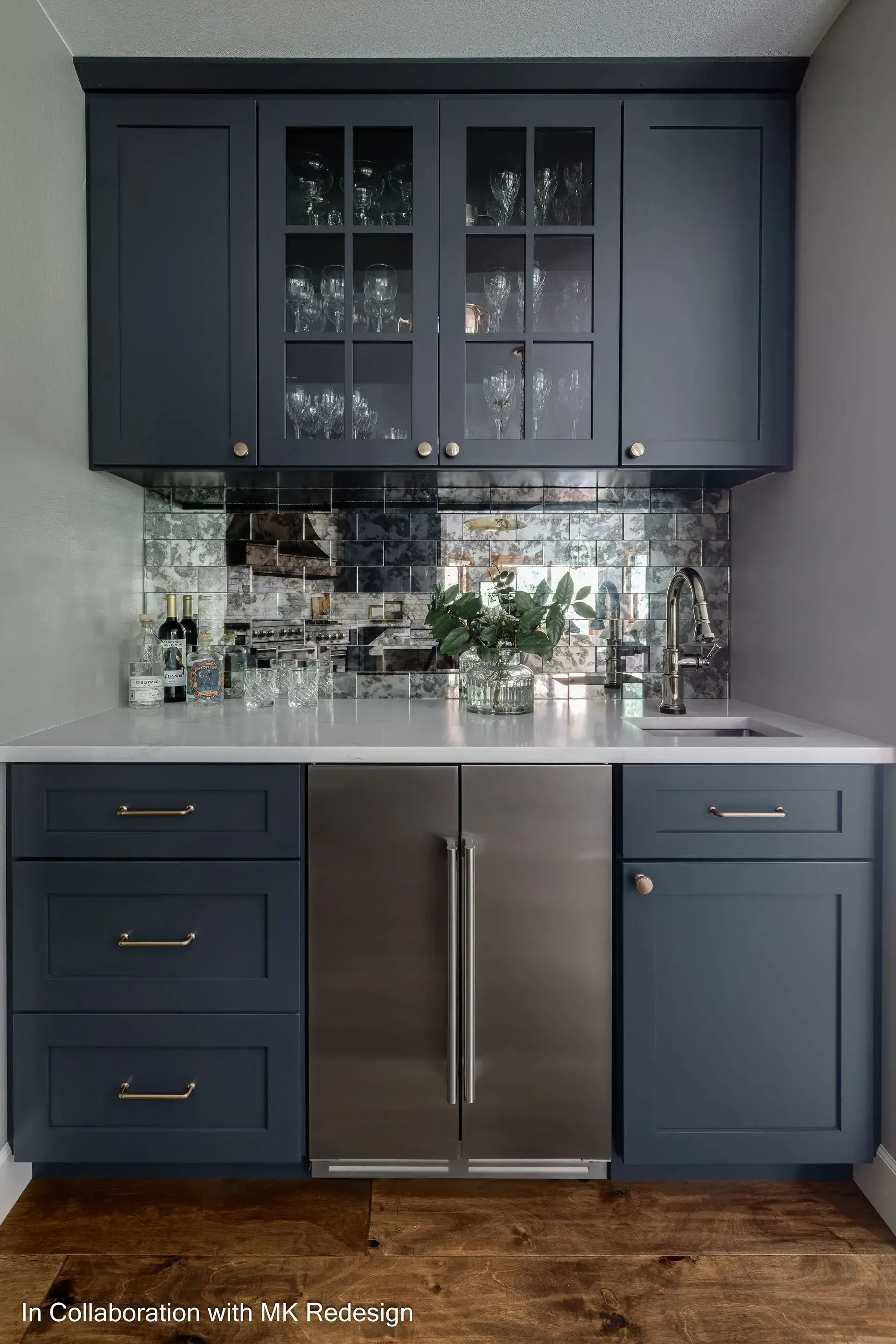 A kitchen with blue cabinets , stainless steel appliances , a sink and a refrigerator.