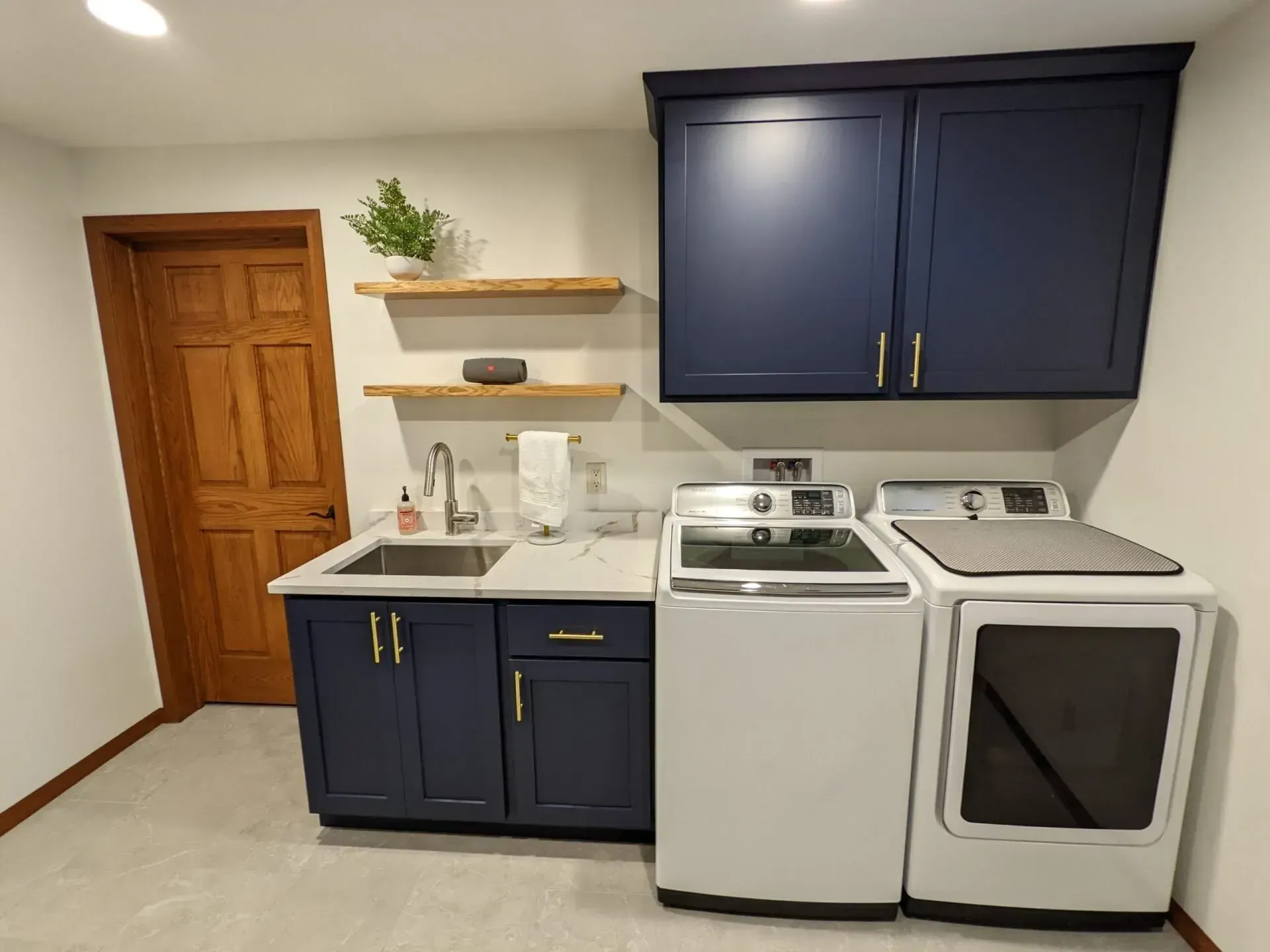 A laundry room with a sink , washer and dryer , and blue cabinets.