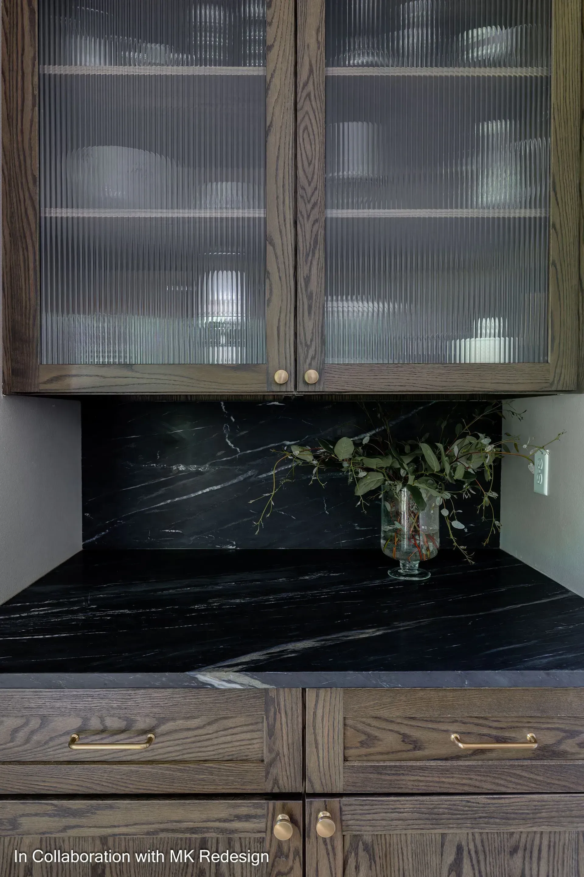 A kitchen with a glass cabinet and a black counter top.