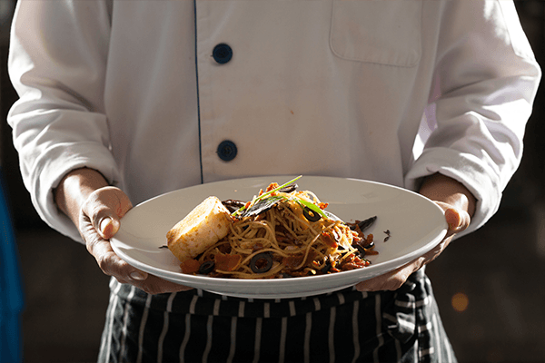 chef holding pasta dish