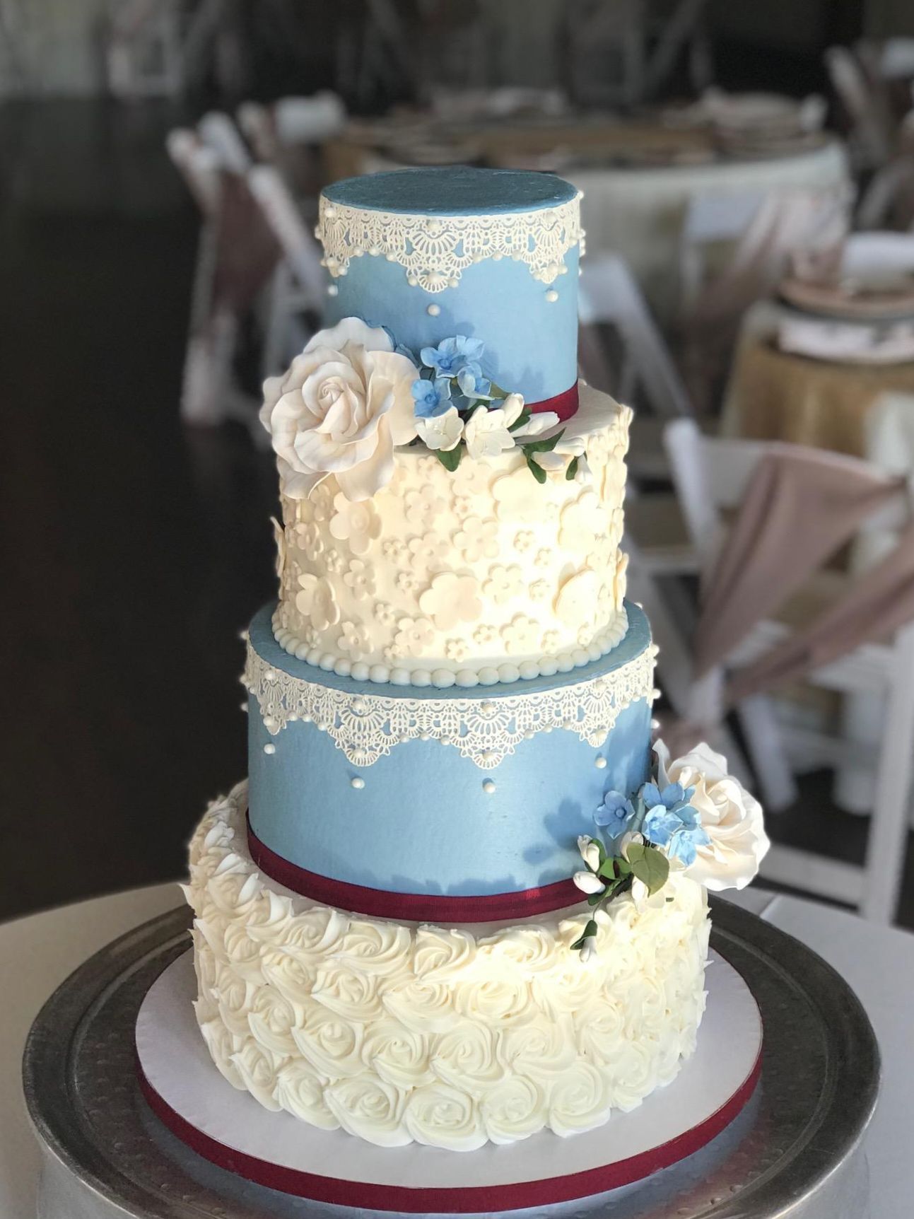 A wedding cake is sitting on a silver plate on a table.