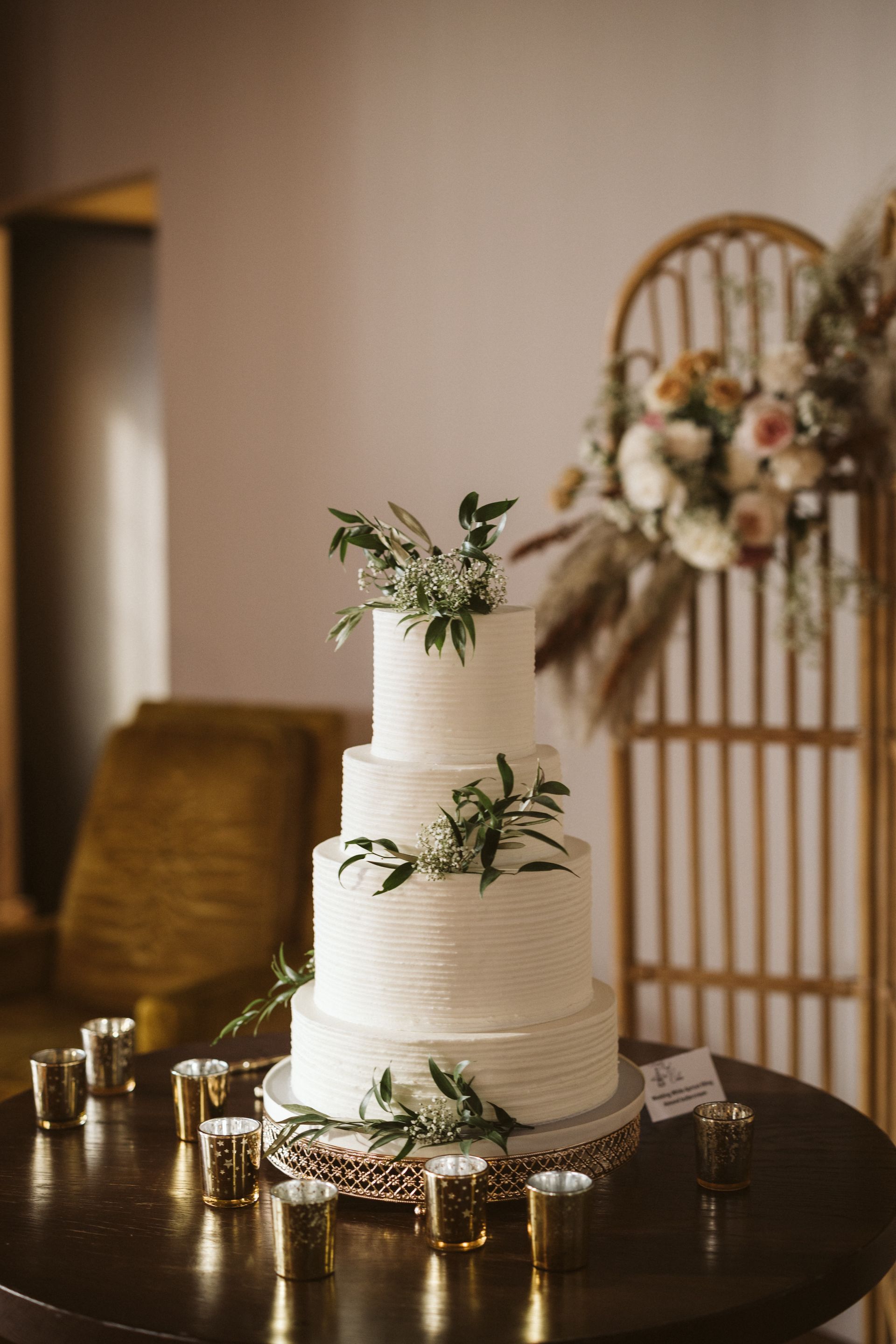 A white wedding cake is sitting on top of a wooden table.