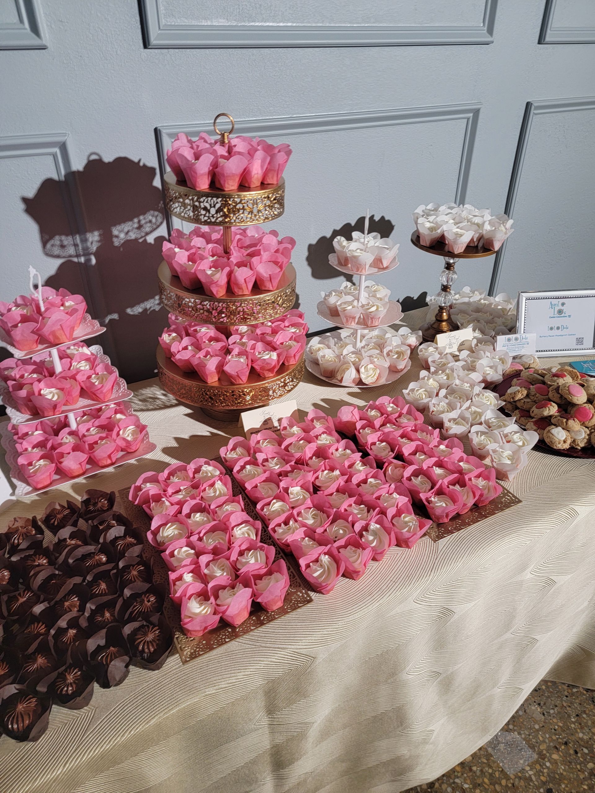 A table topped with lots of pink cupcakes and chocolates.