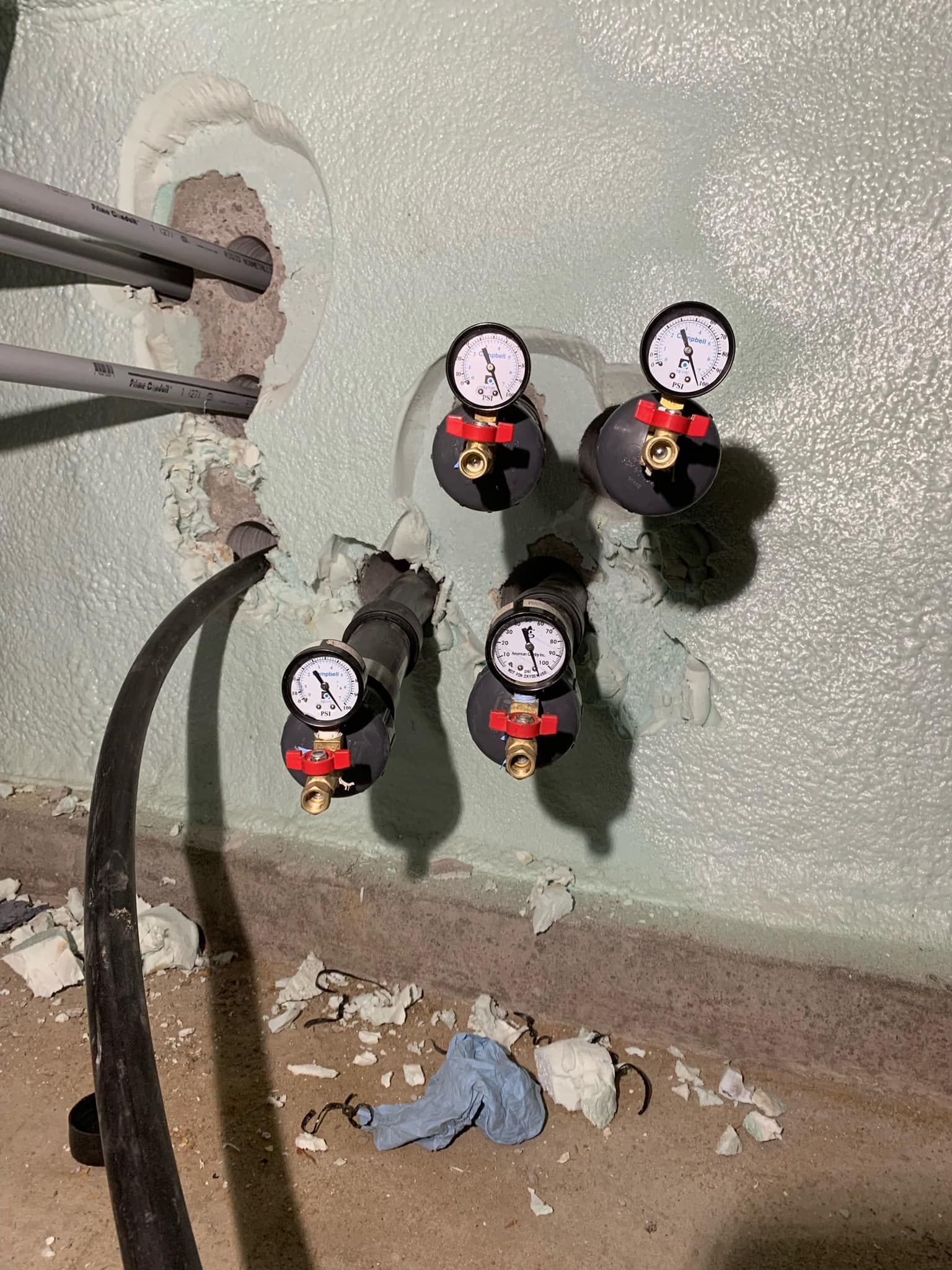 A bunch of pressure gauges are hanging on a wall.