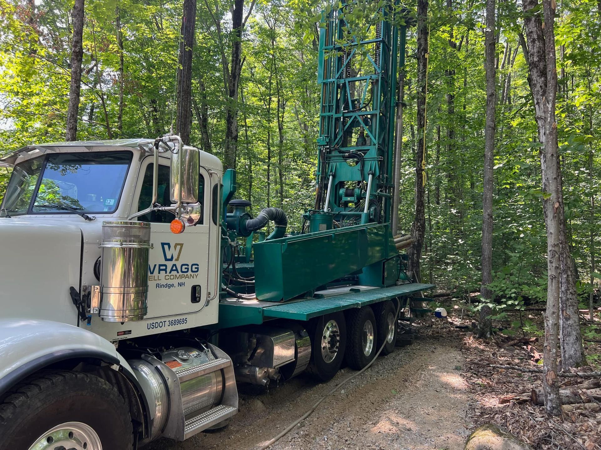 A semi truck is parked on a dirt road in the woods.
