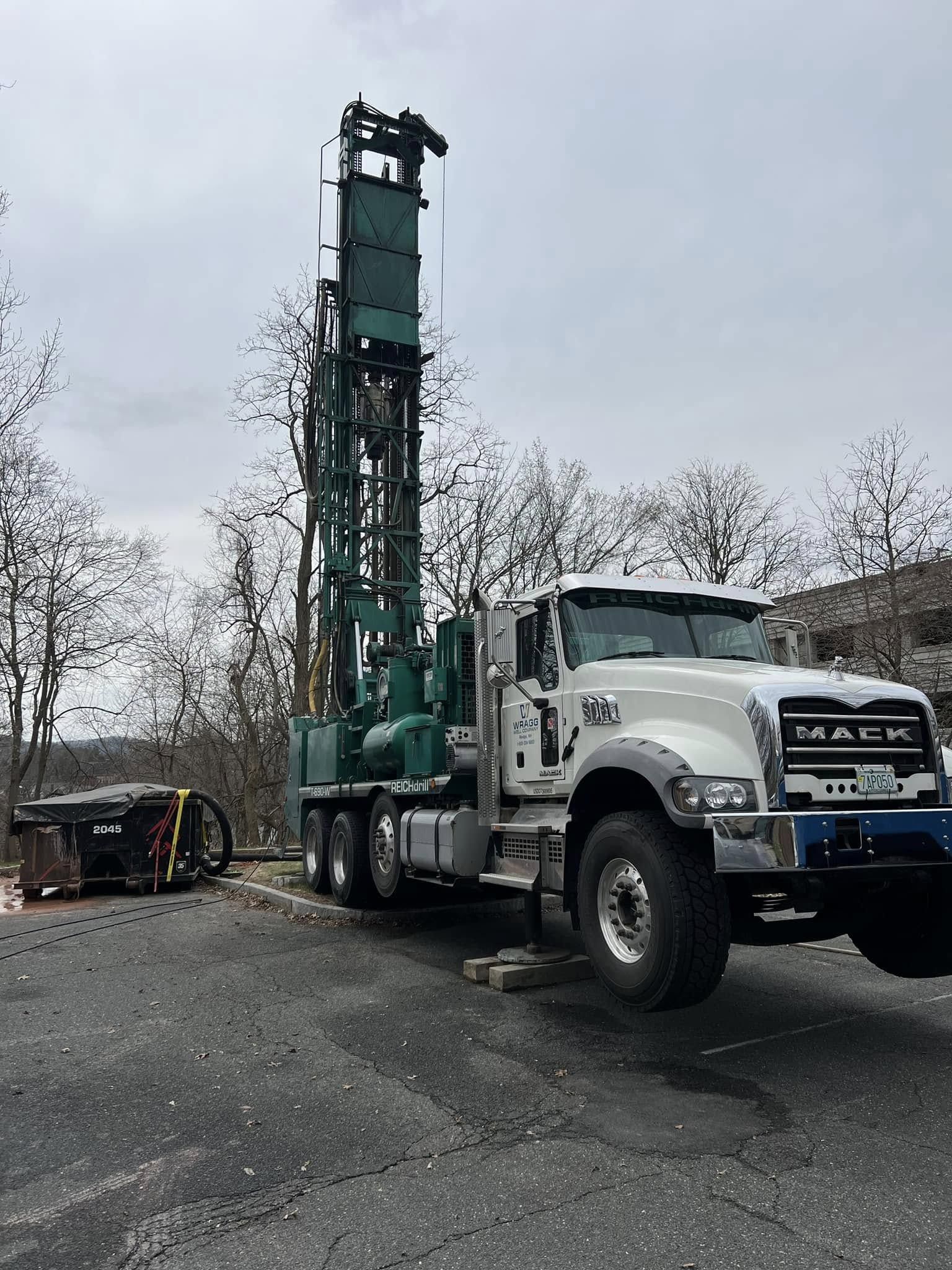 A truck with a drill on the back of it is parked in a parking lot.
