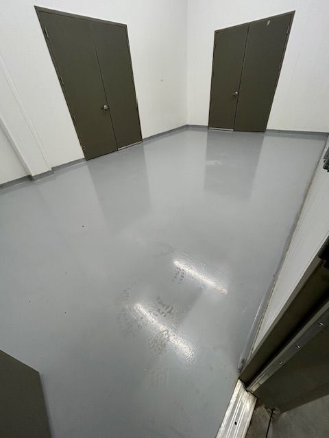 A room with a gray floor and two doors.