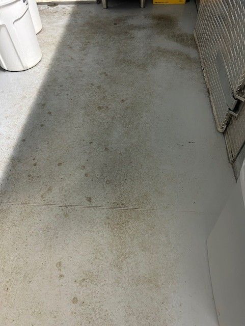 A dirty concrete floor with a yellow trash can in the background.