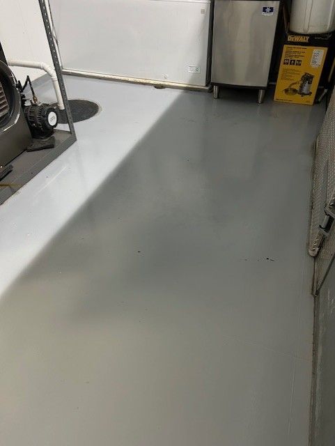 A garage with a concrete floor and a stainless steel refrigerator.