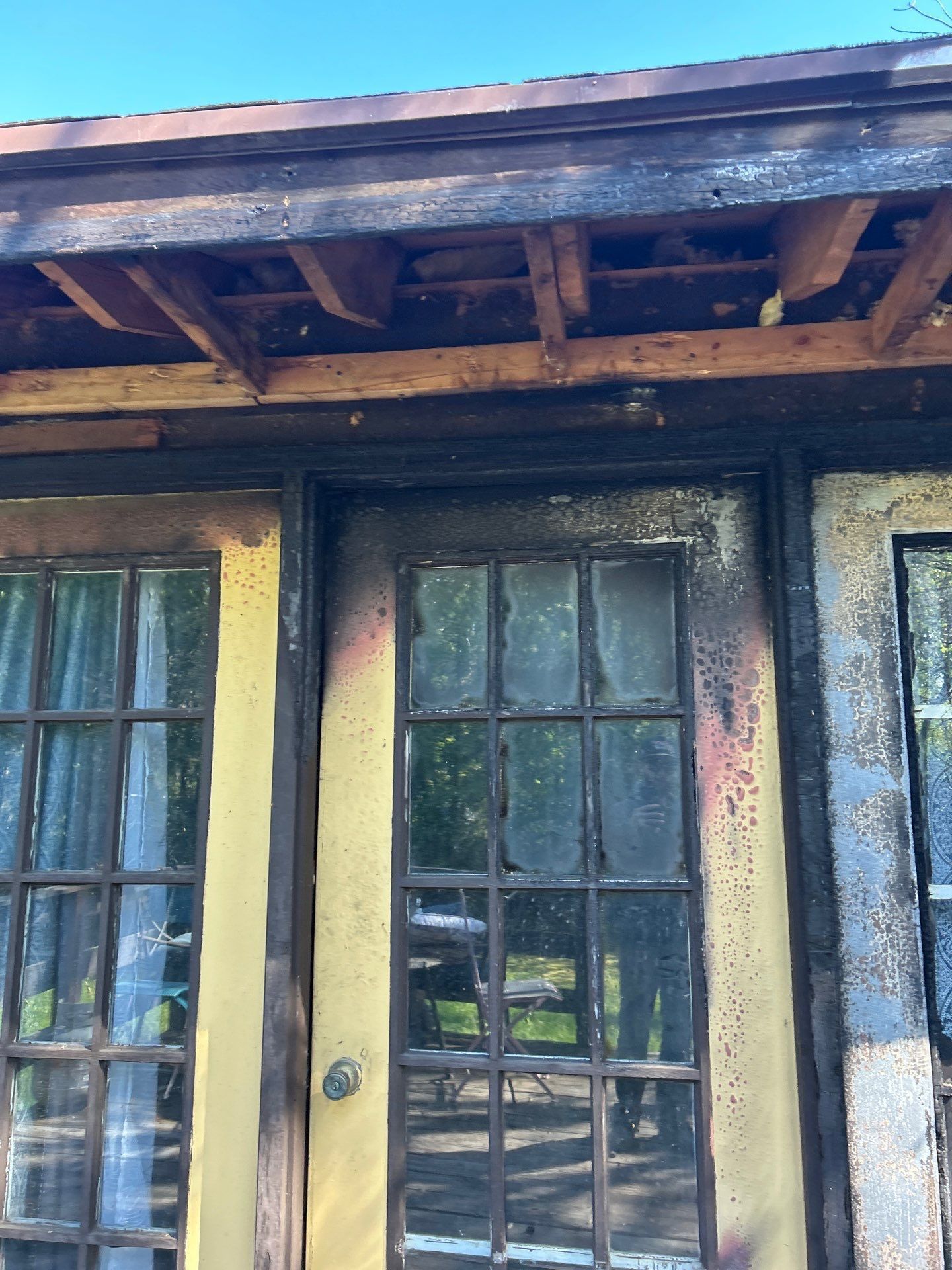 Wooden porch with weathered beams and a glass-paneled door in warm sunlight