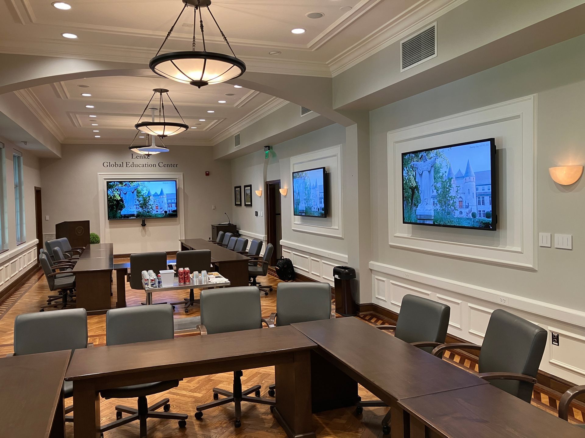 A conference room with a long table and chairs and two televisions on the wall.