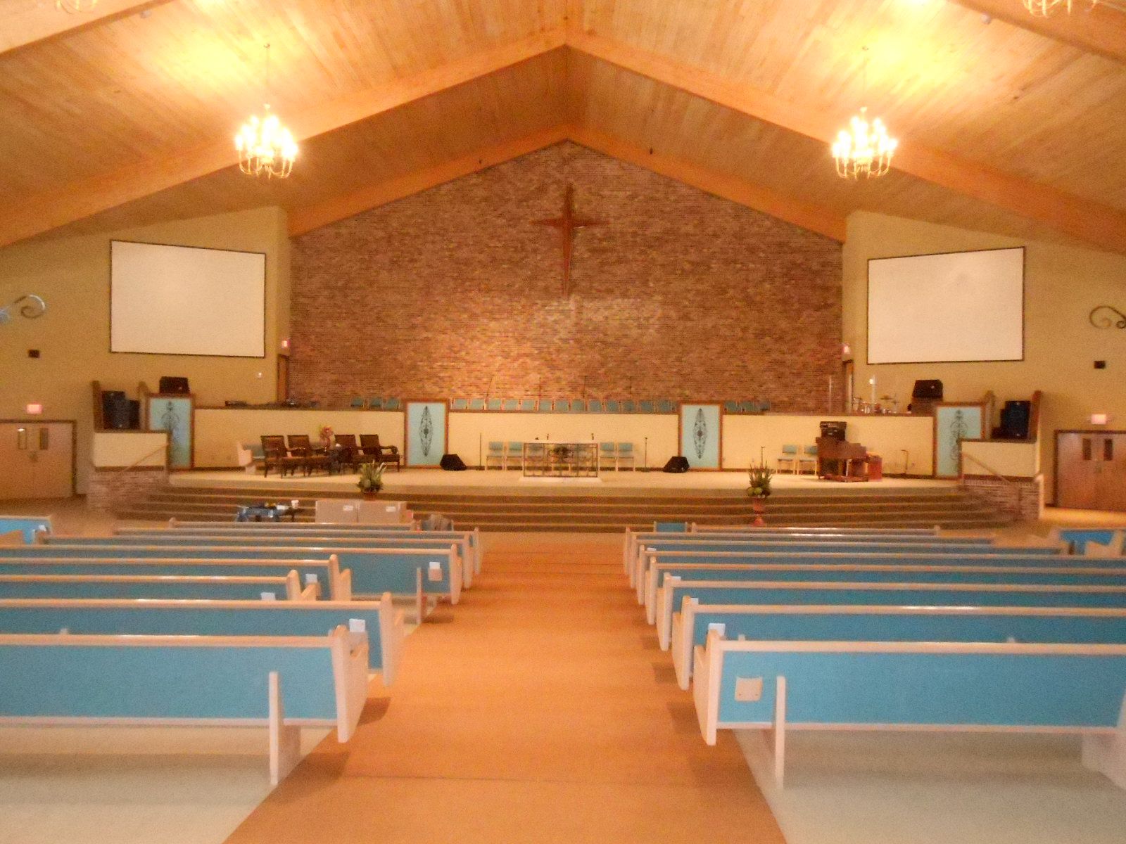 An empty church with blue benches and a brick wall