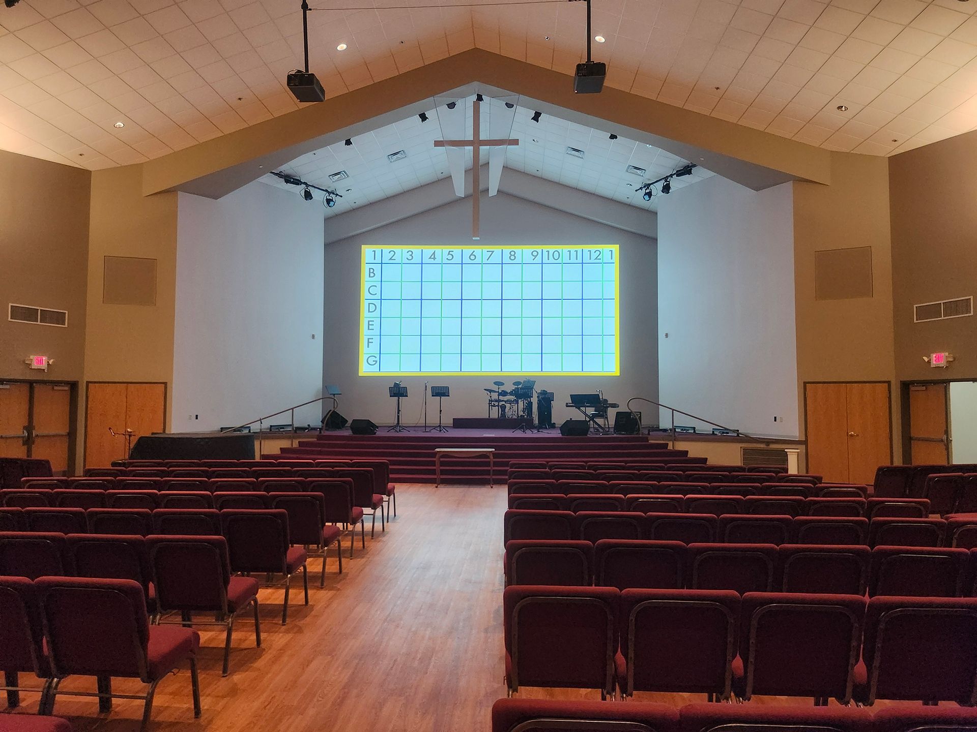 An empty church with red chairs and a large screen on the wall