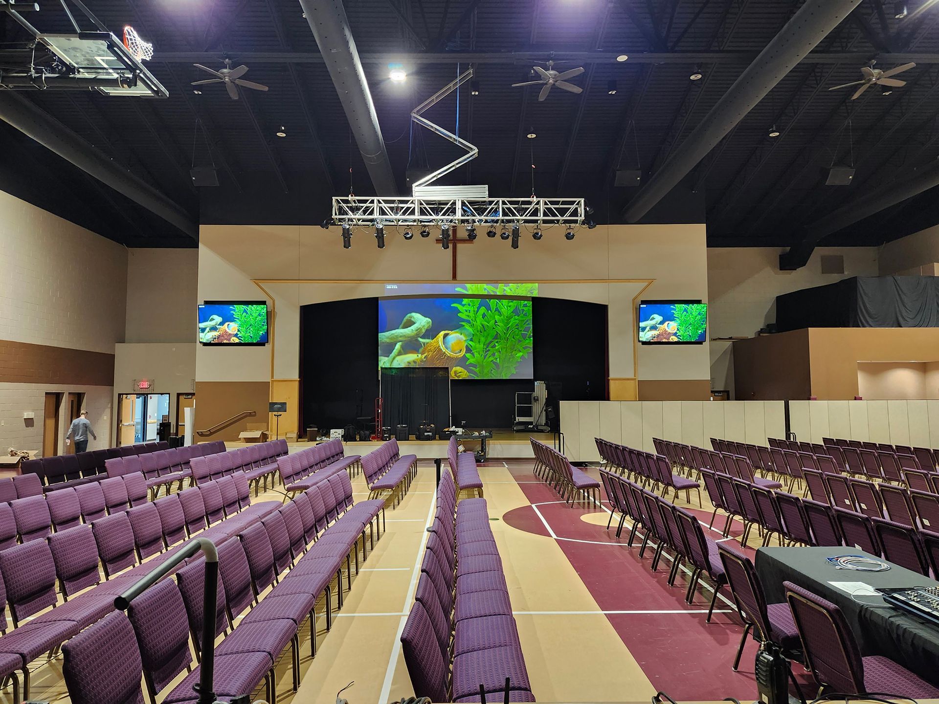 A large auditorium with rows of purple chairs and a large screen.