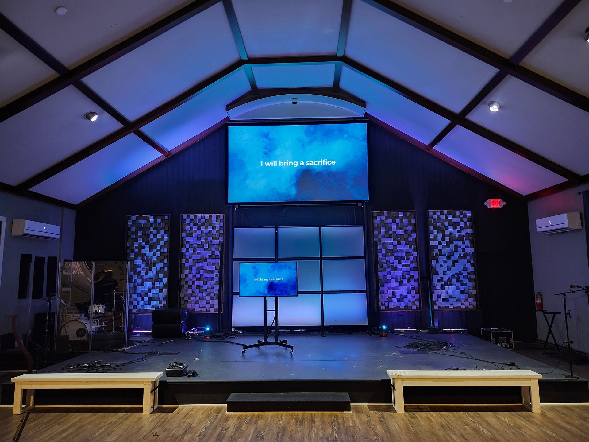 A large screen is hanging from the ceiling of a church.