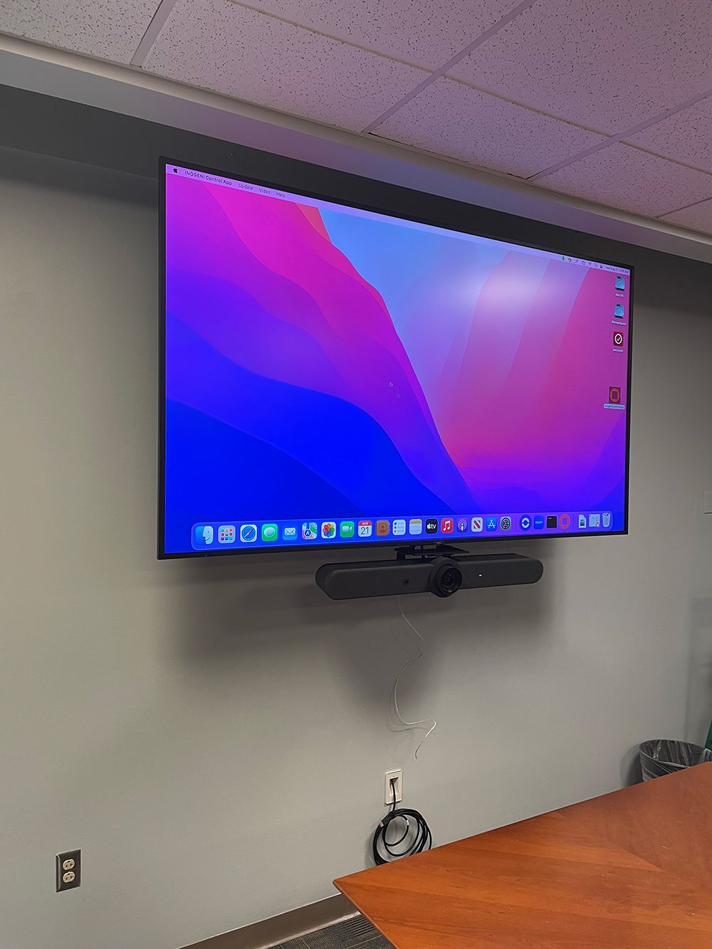 A large flat screen tv is hanging on a wall in a conference room.