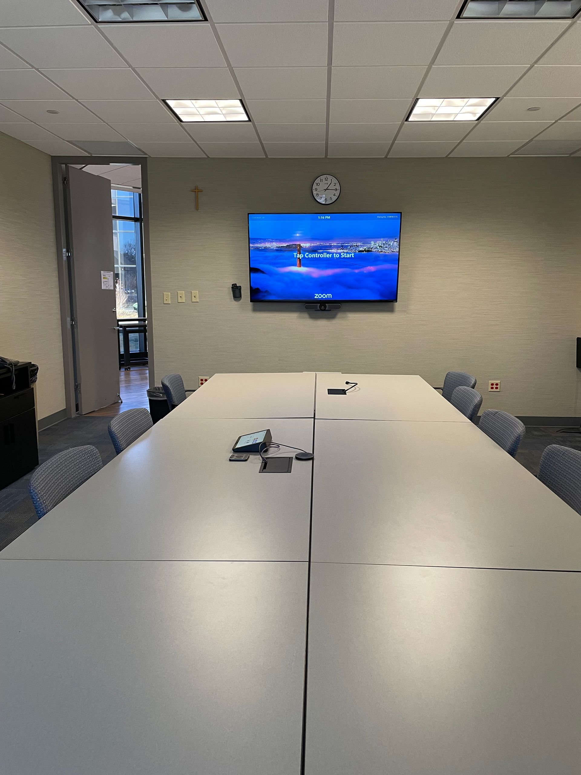 A conference room with a long table and chairs and a flat screen tv on the wall.