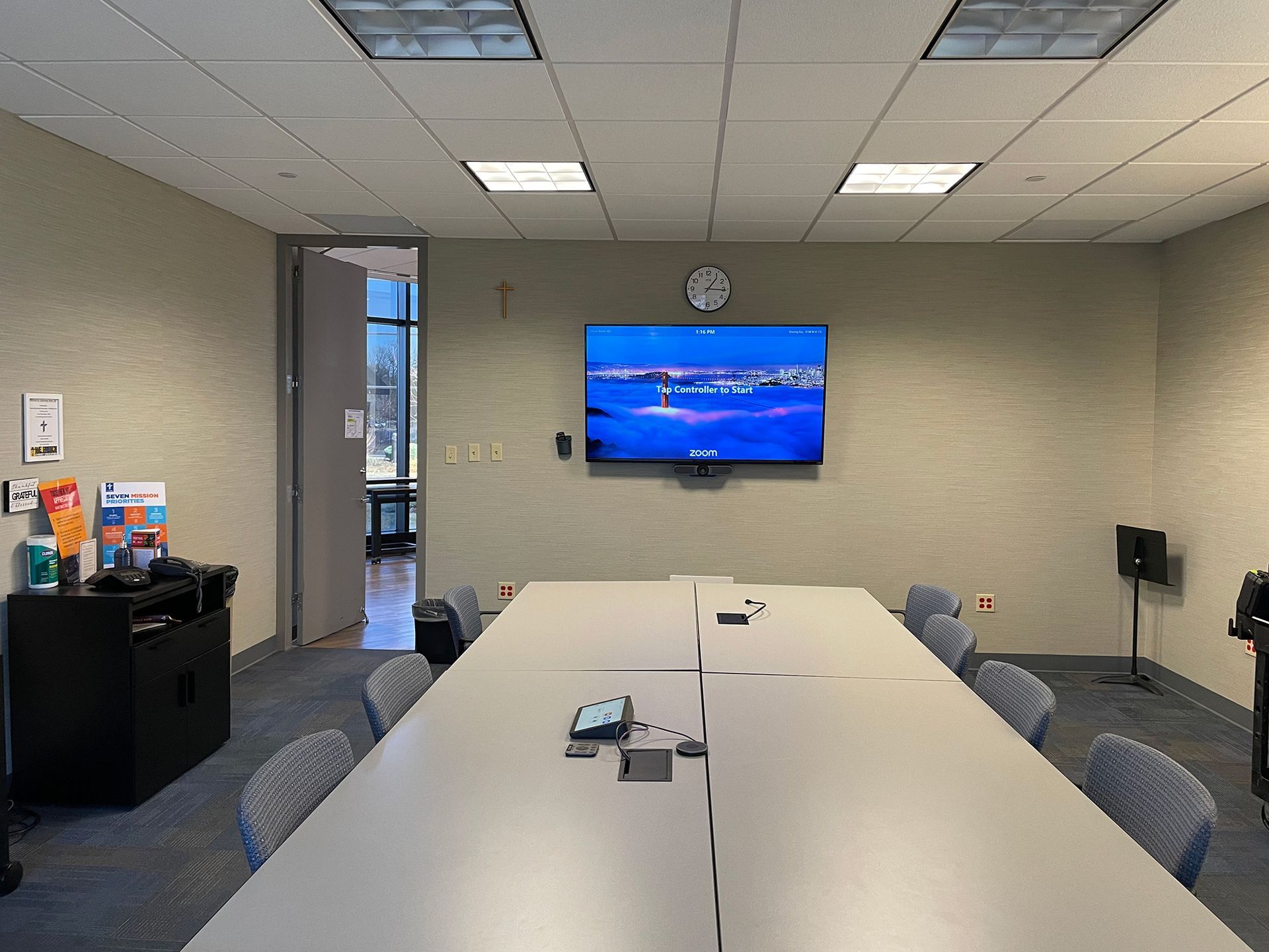 A conference room with a long table and chairs and a flat screen tv on the wall.