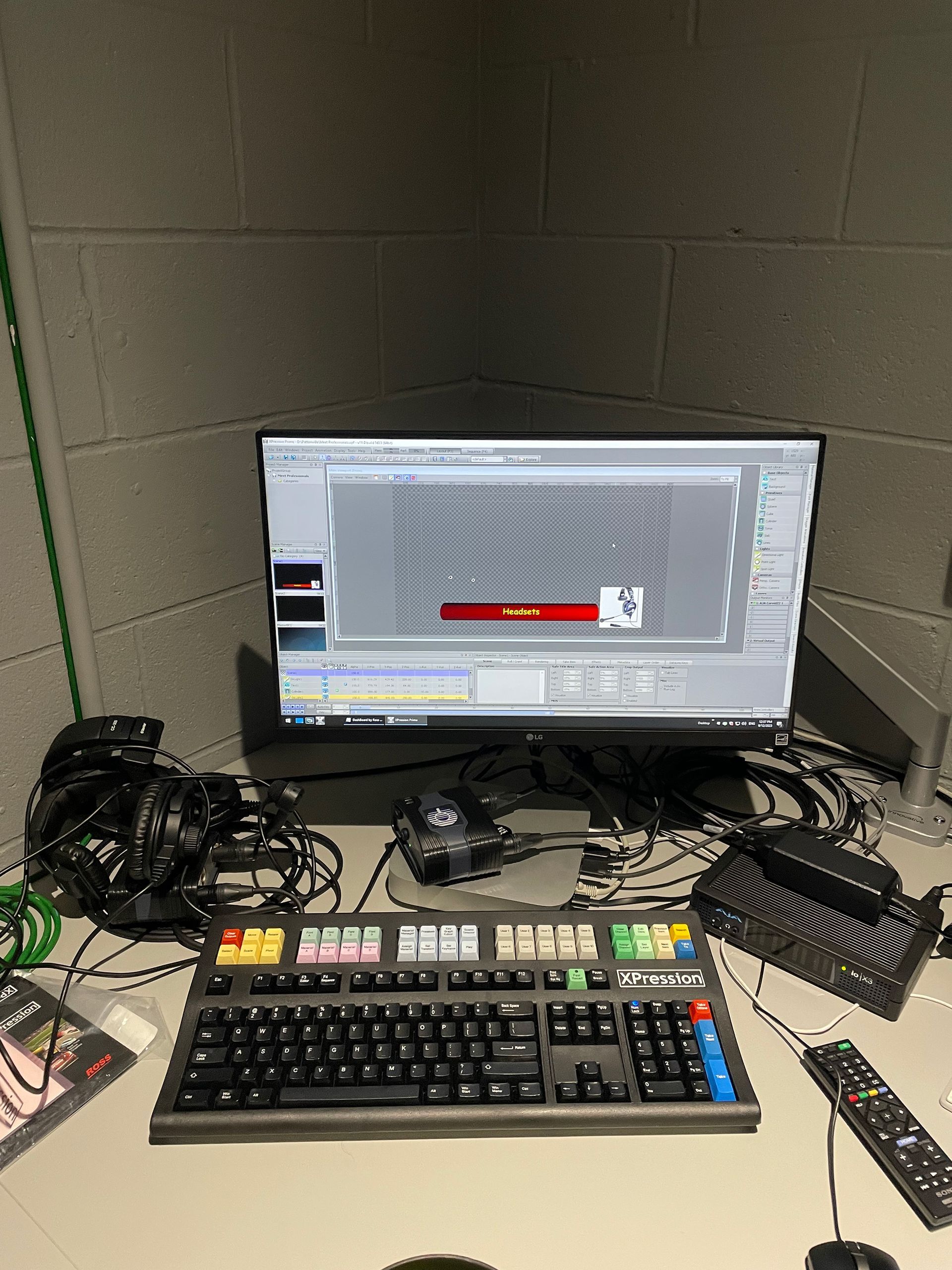 A computer monitor is sitting on a desk next to a keyboard and remote control.