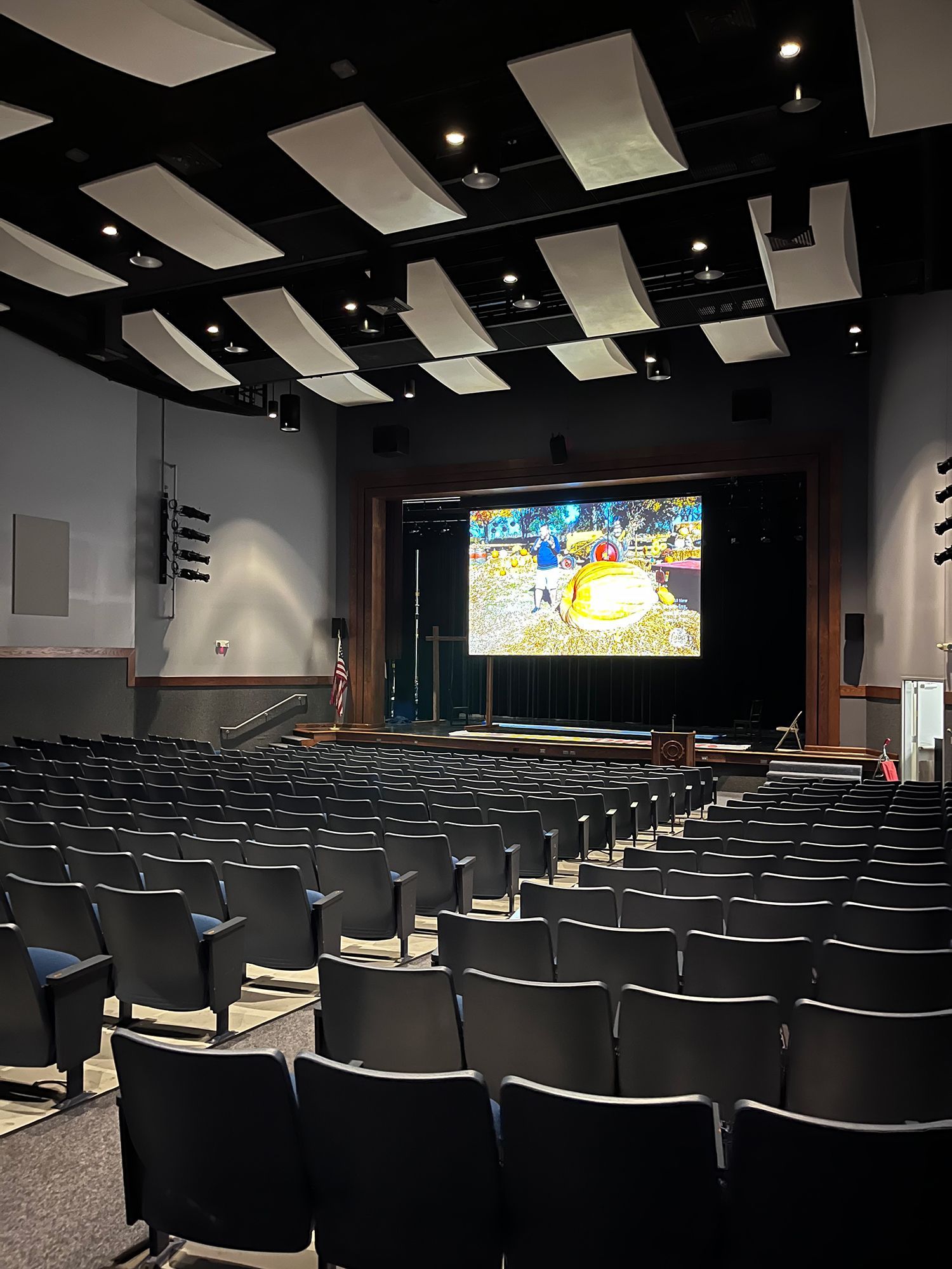 An auditorium with empty seats and a large screen on the stage