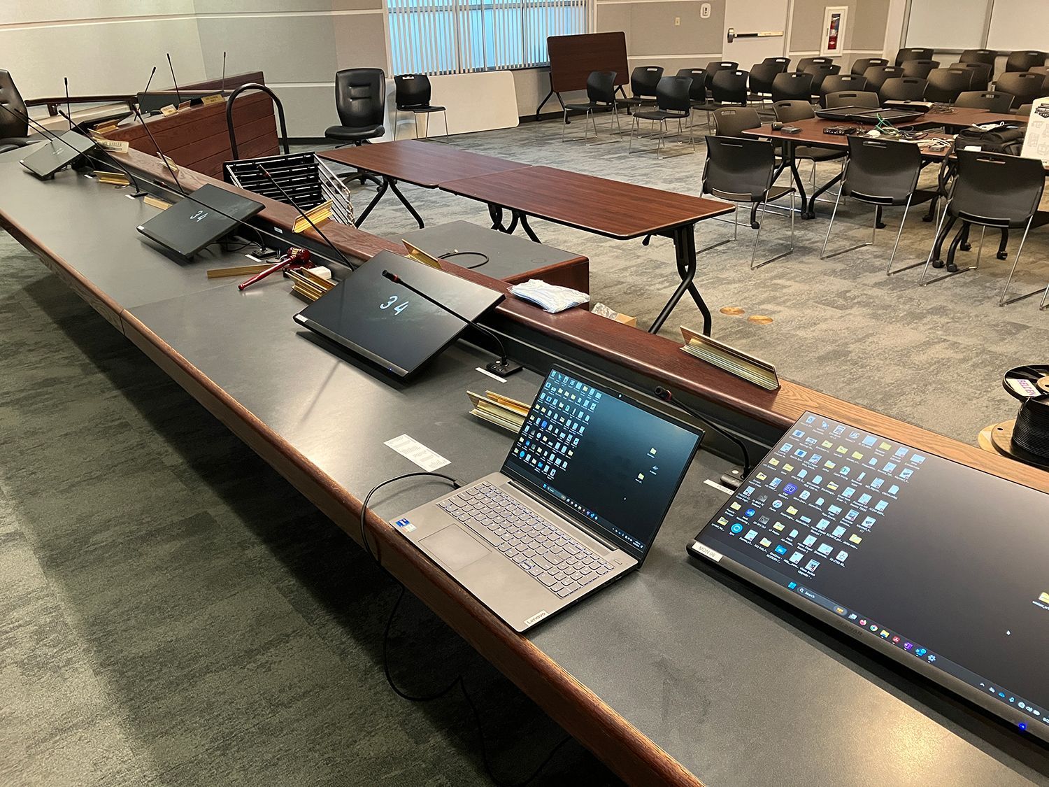 Two laptops are sitting on a long table in a conference room.