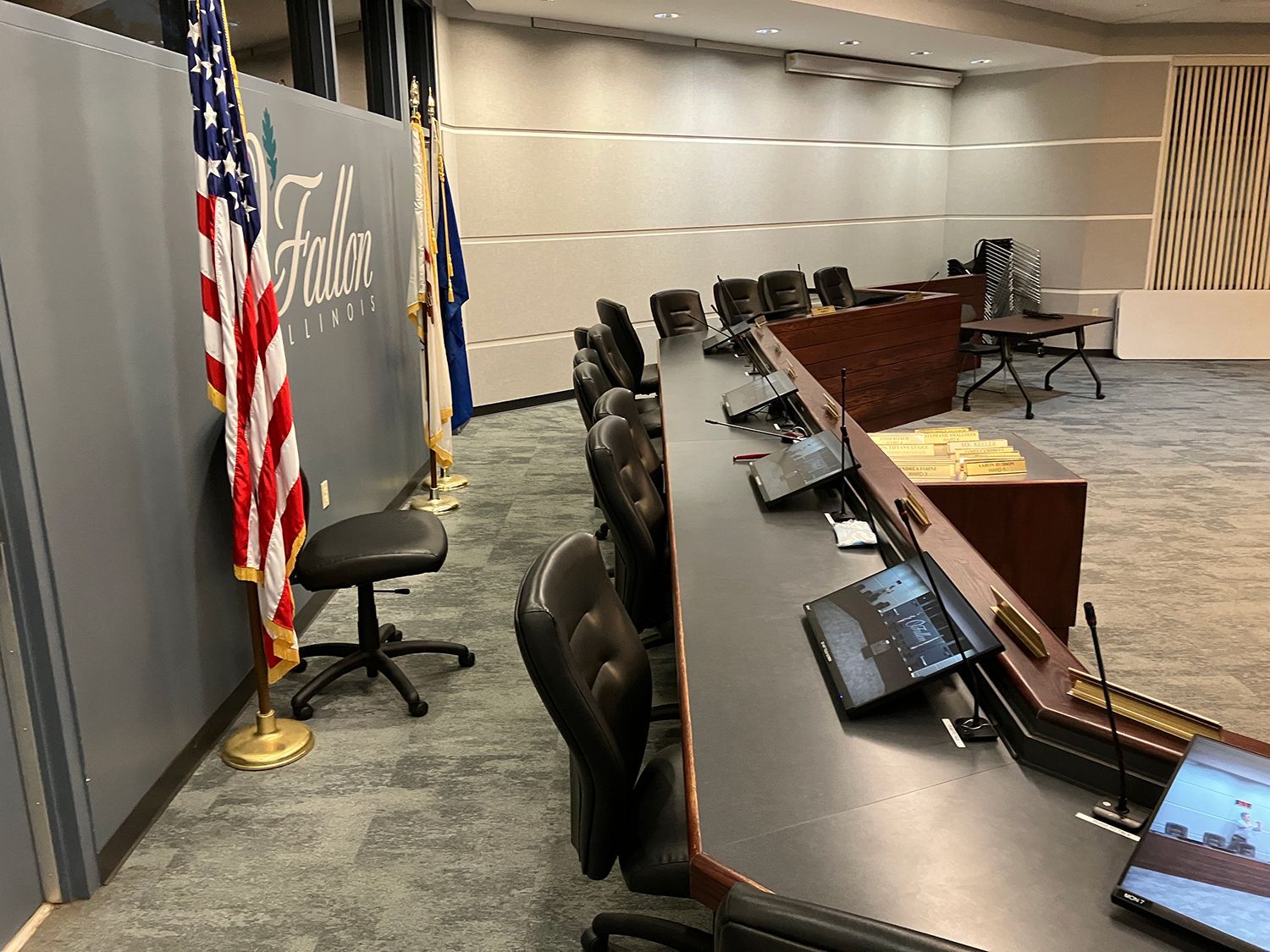 A conference room with a long table and chairs and an american flag on the wall.